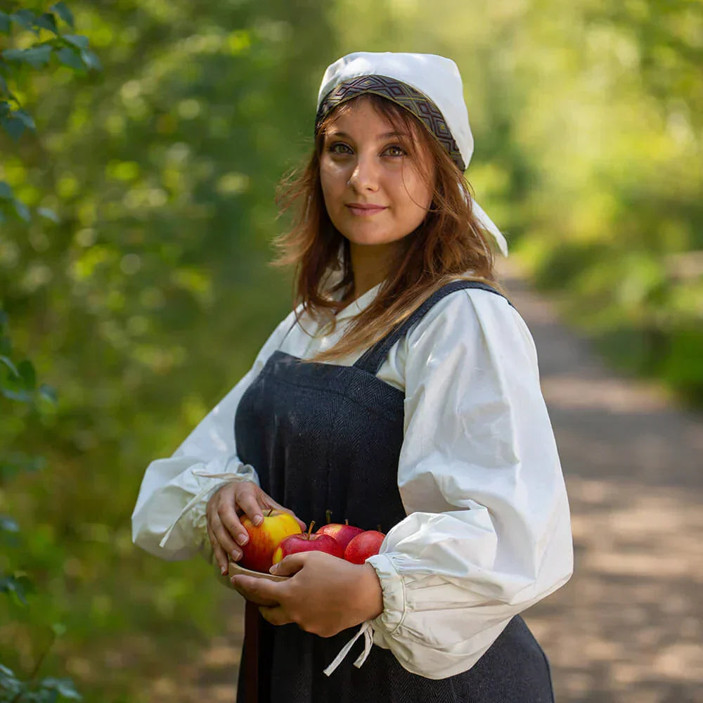 Woman in a countryside setting holding apples, demonstrating traditional farming lifestyle.