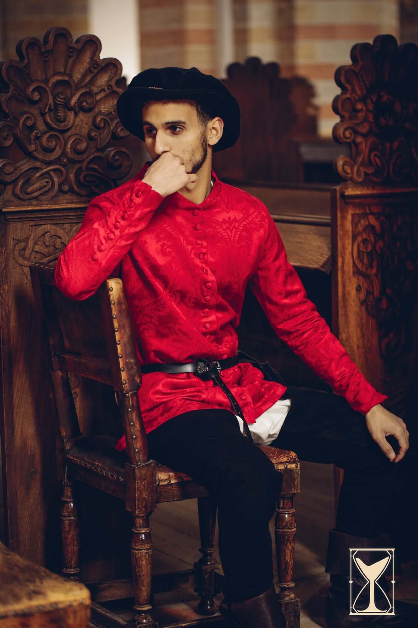 A man in a red medieval cotehardie in an indoor setting