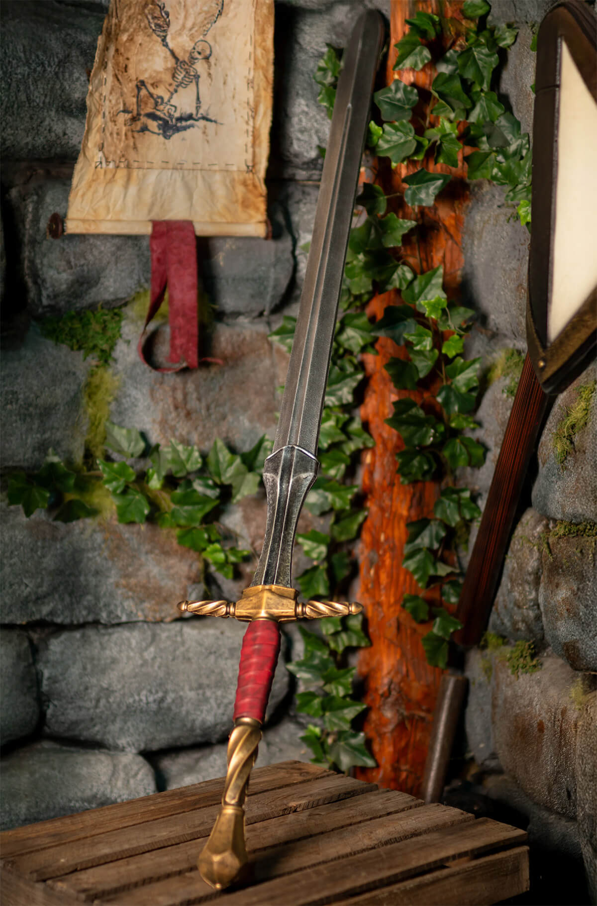 A detailed view of a long sword with a golden hilt and red grip, highlighted against a rustic stone wall.