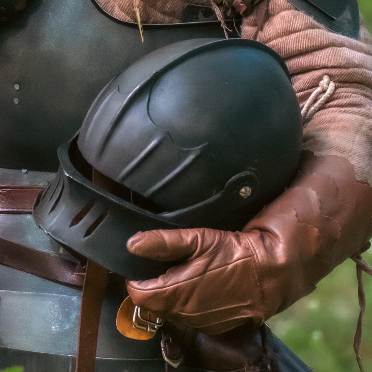 Medieval & Knight Helmets, a black helmet held by a person in period costume with brown gloves.
