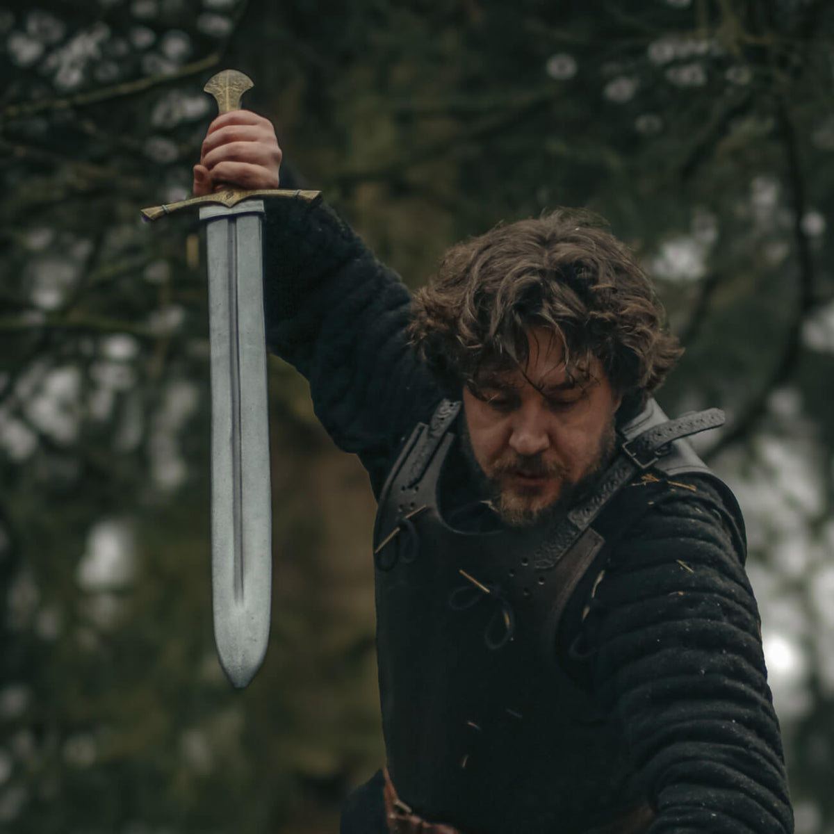 Man wielding a short sword in an action pose amidst trees, demonstrating the agility of short swords.