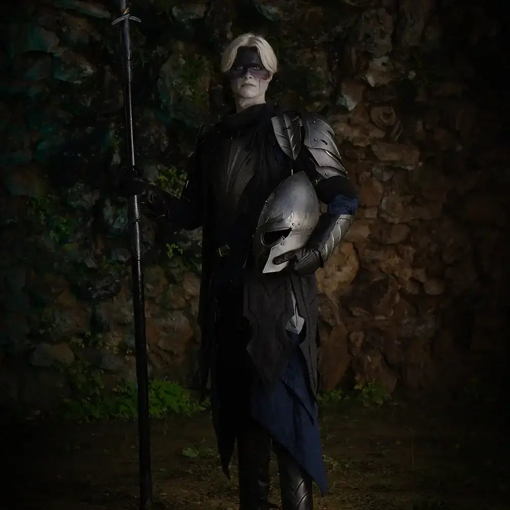 A fantasy warrior in dark armor holding a spear and helmet, set against a stone wall background.