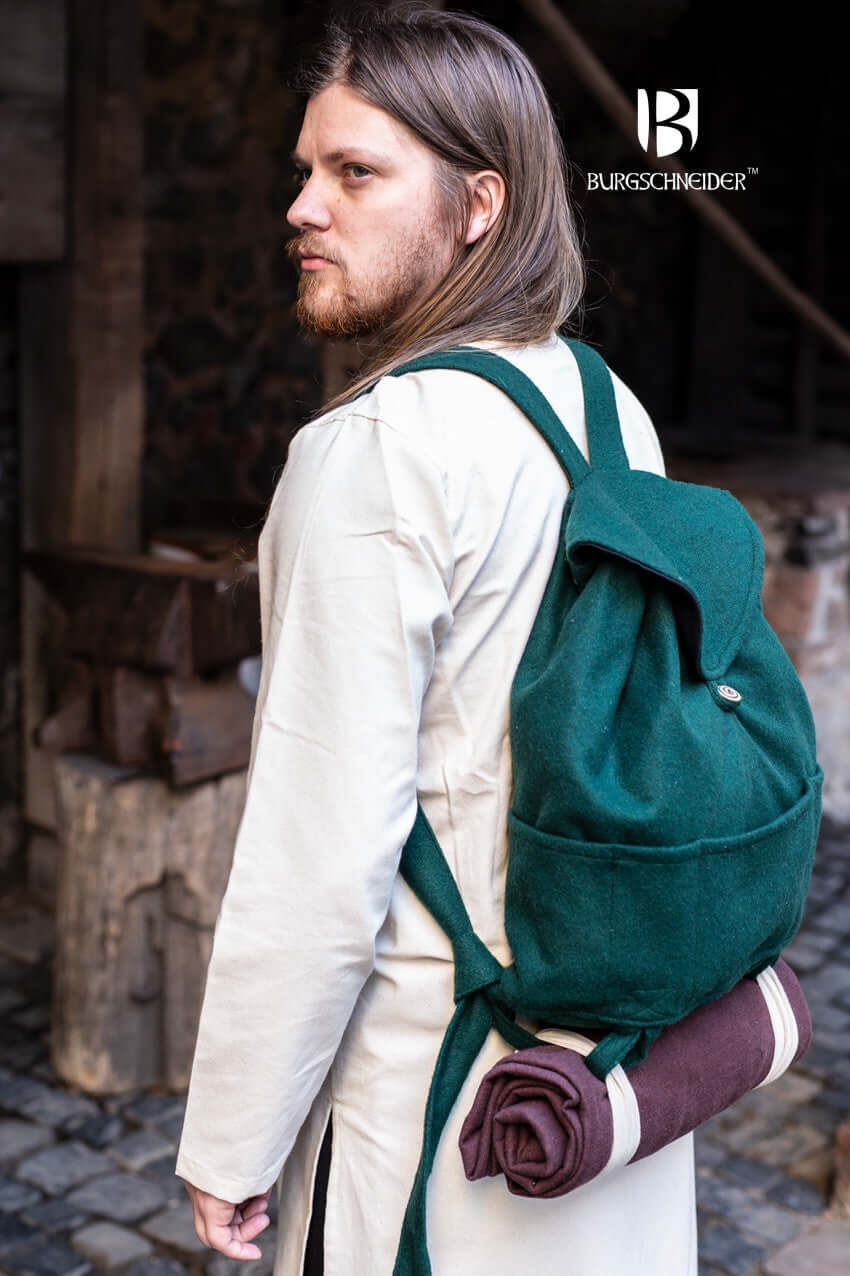 A traveler wearing a green Backpack Robin while carrying a sleeping roll, showcasing its practicality for outdoor adventures.