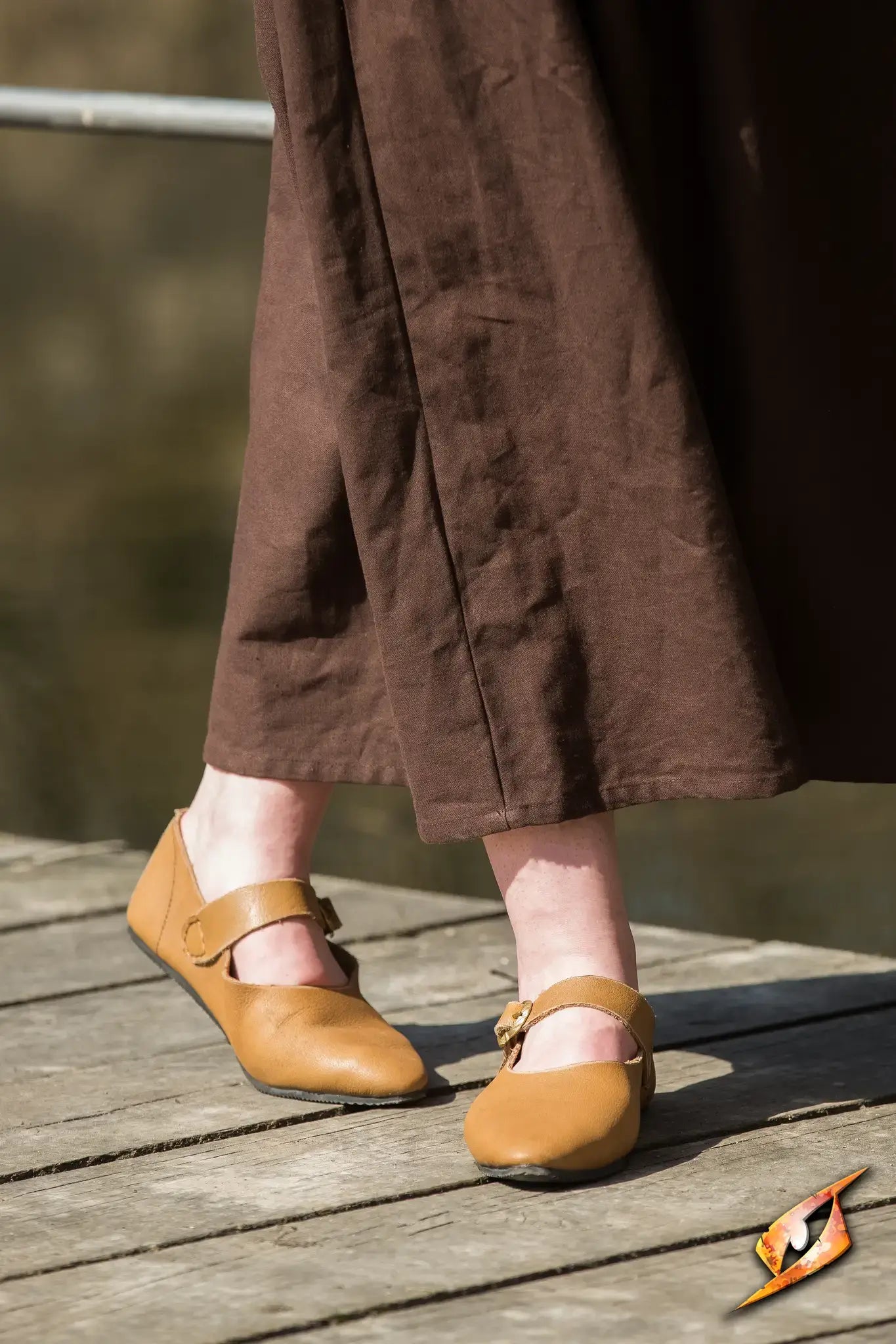 Shoes Astrid styled in brown leather, featuring a comfortable fit with a single leather strap on a wooden pathway.