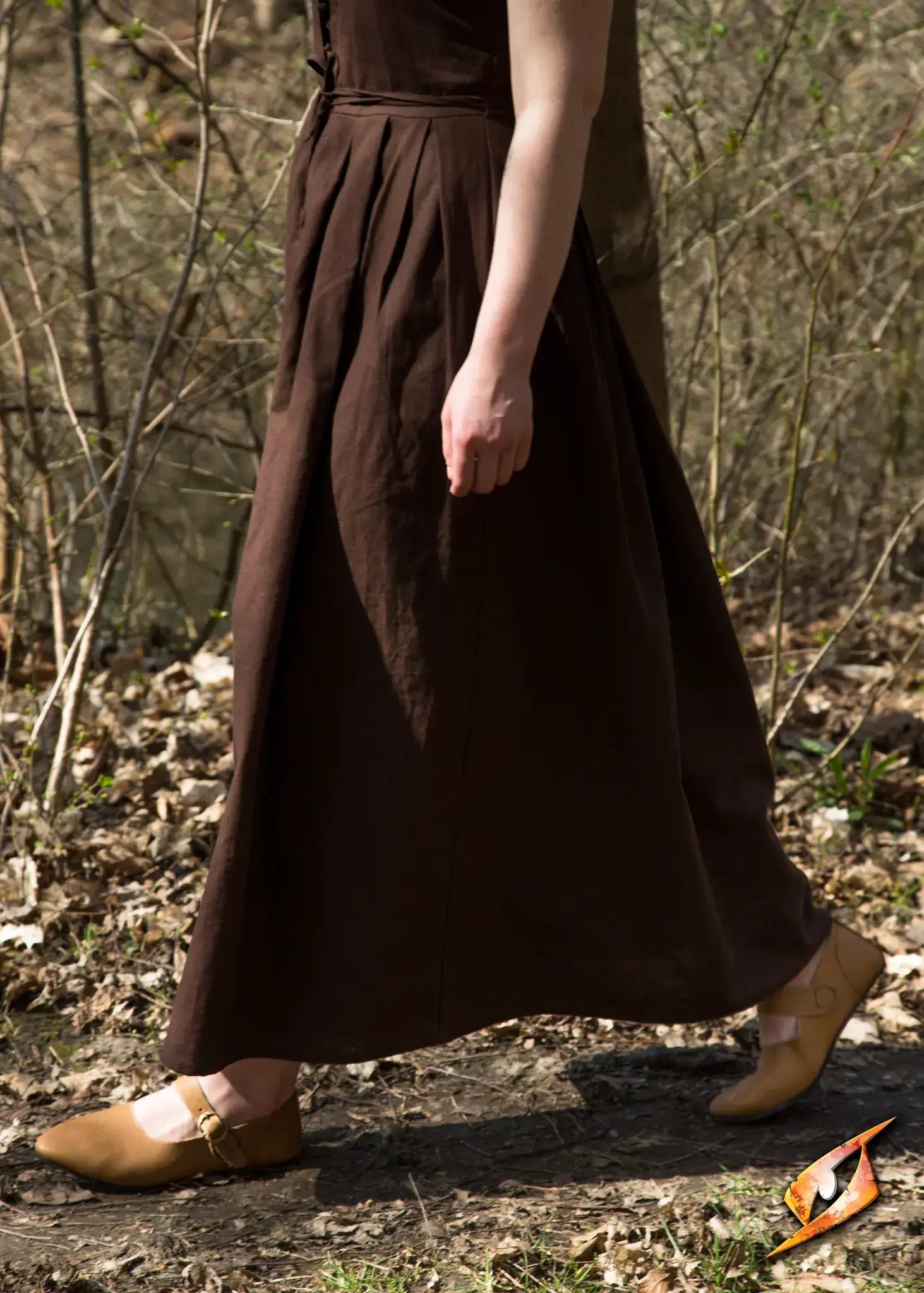 A woman walking on a trail wearing Shoes Astrid with a brown dress and natural surroundings.
