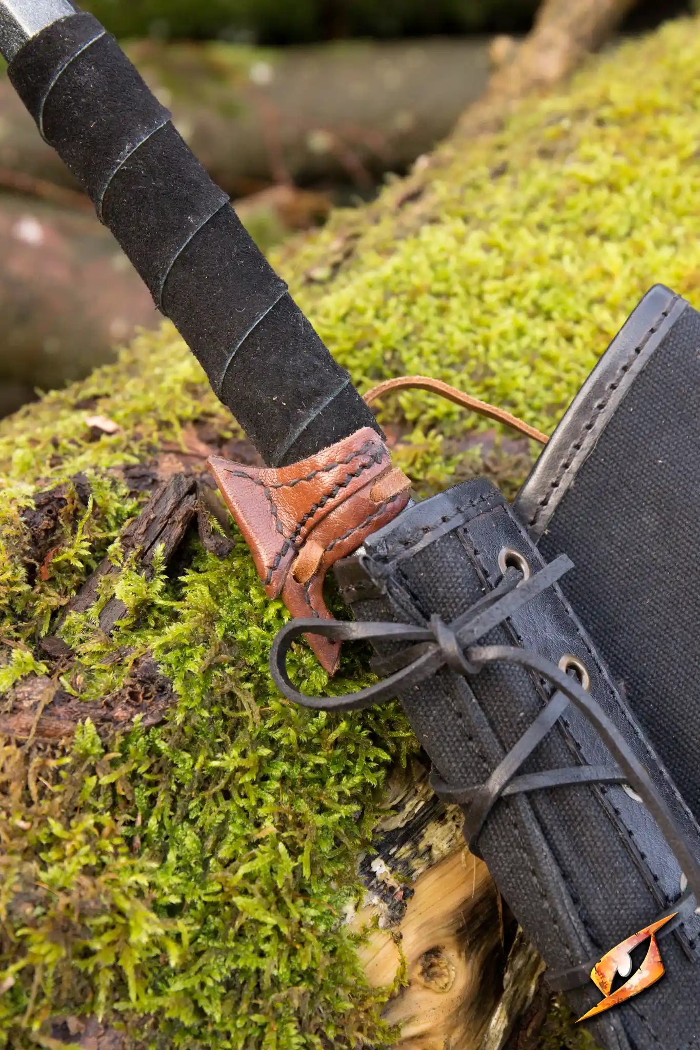 Close-up of an Elven Holster Hook attached to a sword on mossy ground, showcasing its detailed craftsmanship.