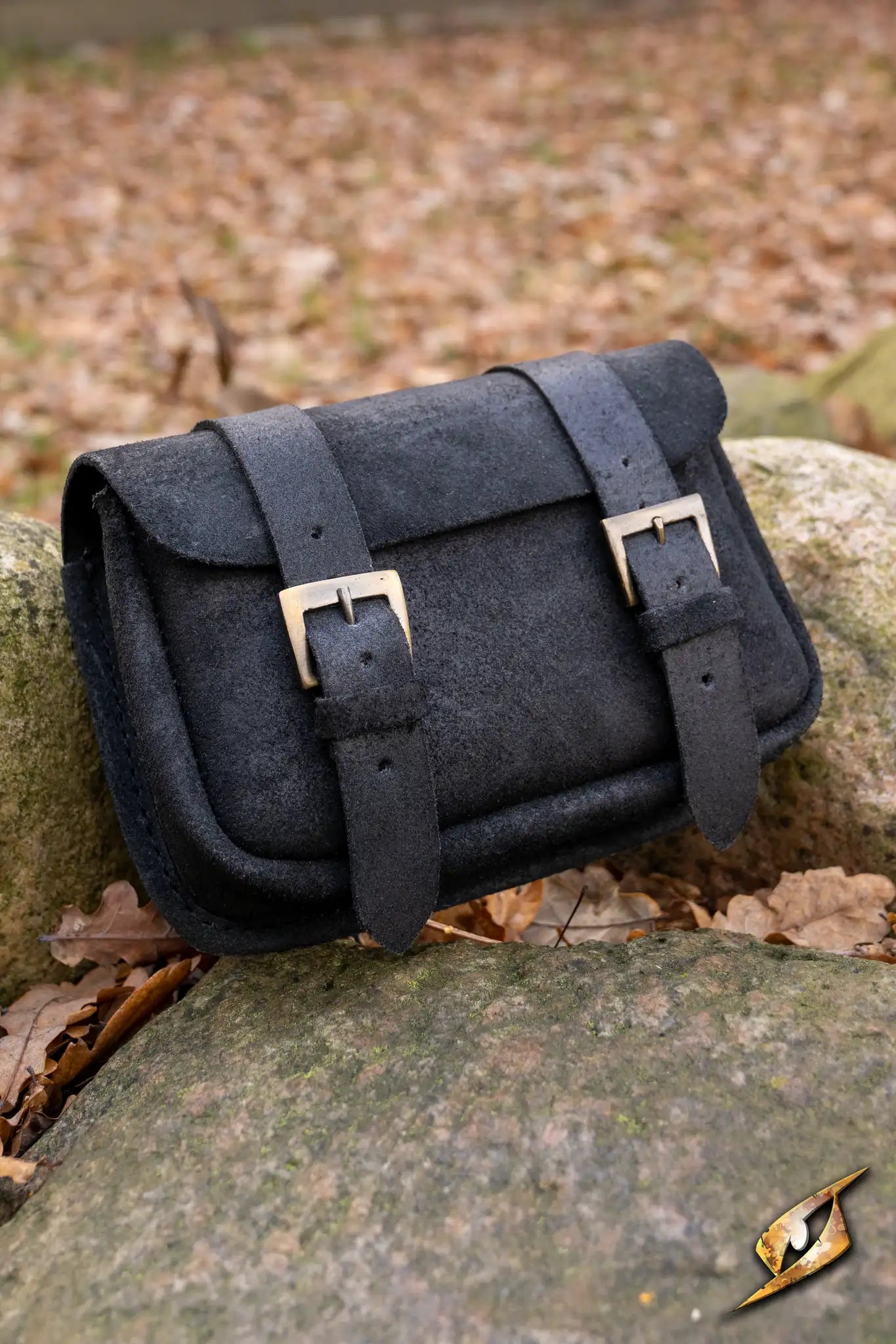 Warrior bag - Suede - Large resting on a rock surrounded by fallen leaves, showcasing its stylish leather design.