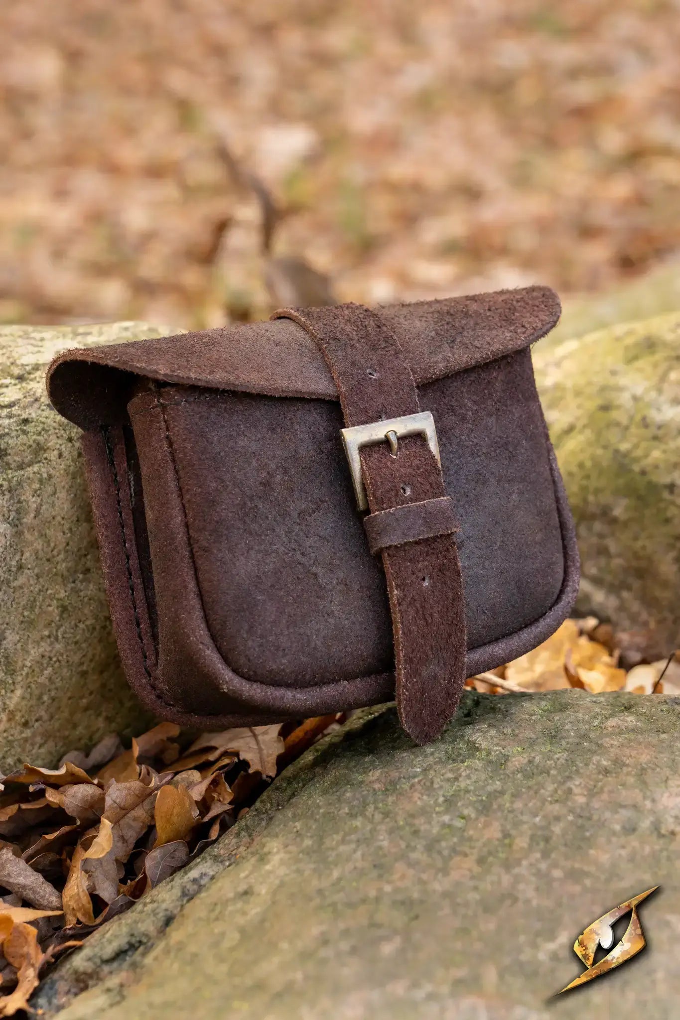 Warrior bag - Suede - Small placed on a rock surrounded by autumn leaves, showcasing durable design.