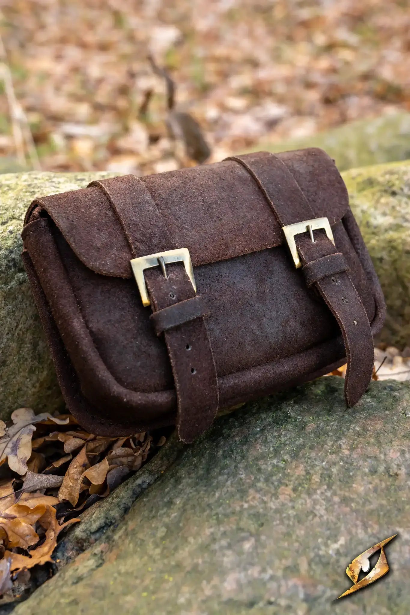 Warrior bag - Suede - Large resting on a rock, showcasing its brown suede material and stylish buckles.