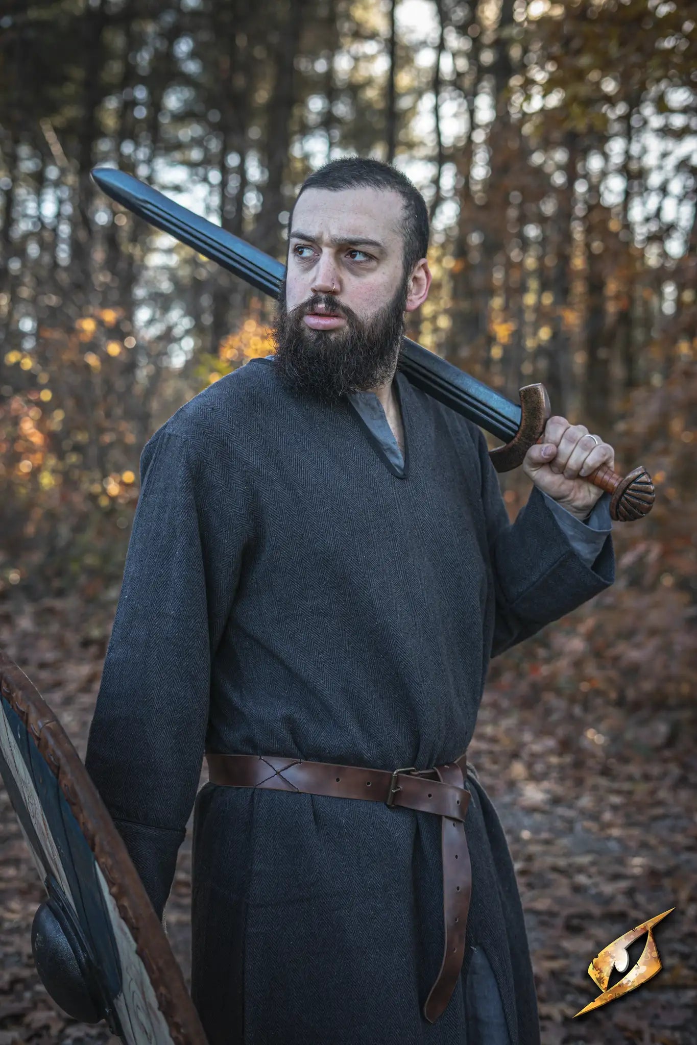 A warrior in a dark tunic wielding a sword and shield, wearing the X Belt - Faux Leather.