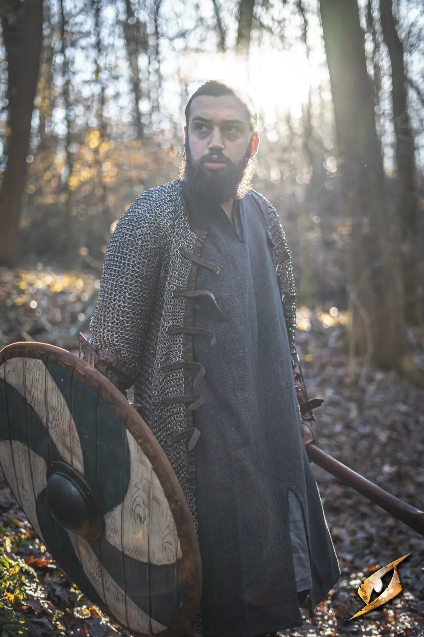 Thegn Shield held by a man in chainmail, standing in a forest during sunset, evoking Viking history.