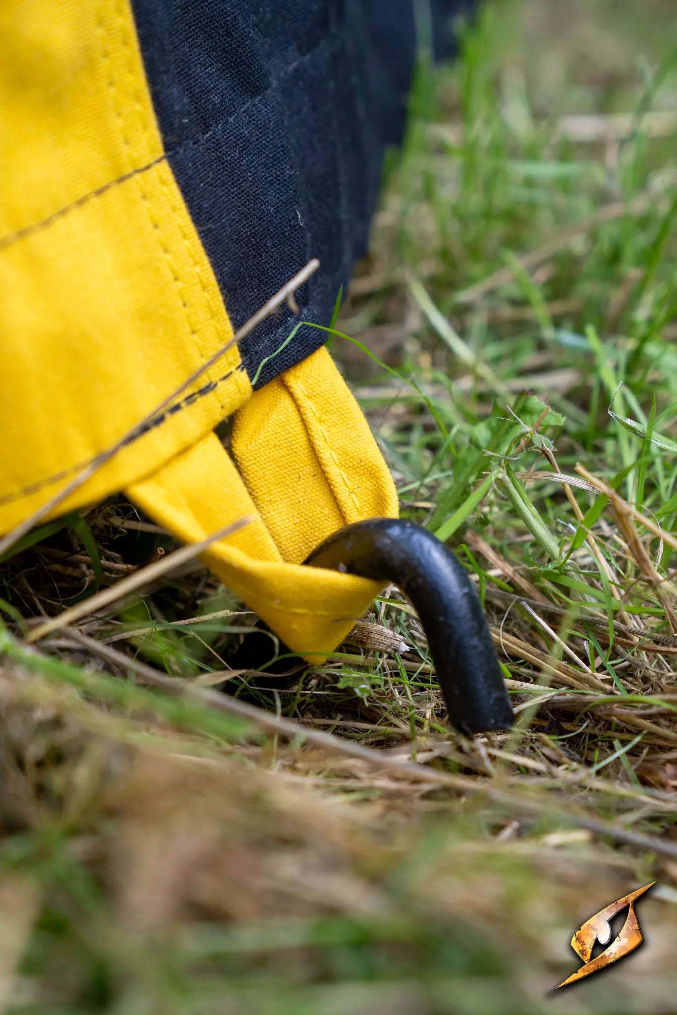 Close-up of a peg securing the Marquee Tent - 4x4m to the ground, showcasing its sturdy design and vibrant color.