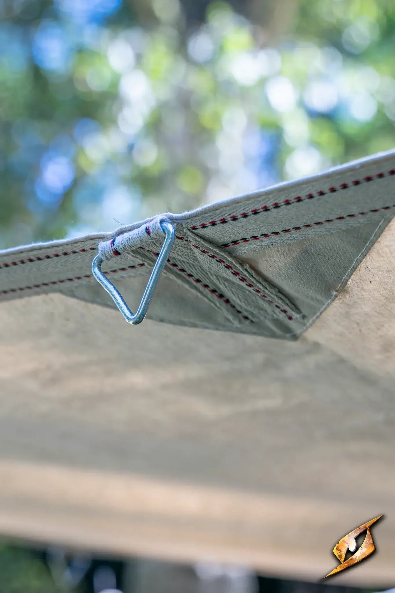 Close-up of a triangular ring attached to the Epic Armoury Tarpaulin fabric, showcasing durability and design.