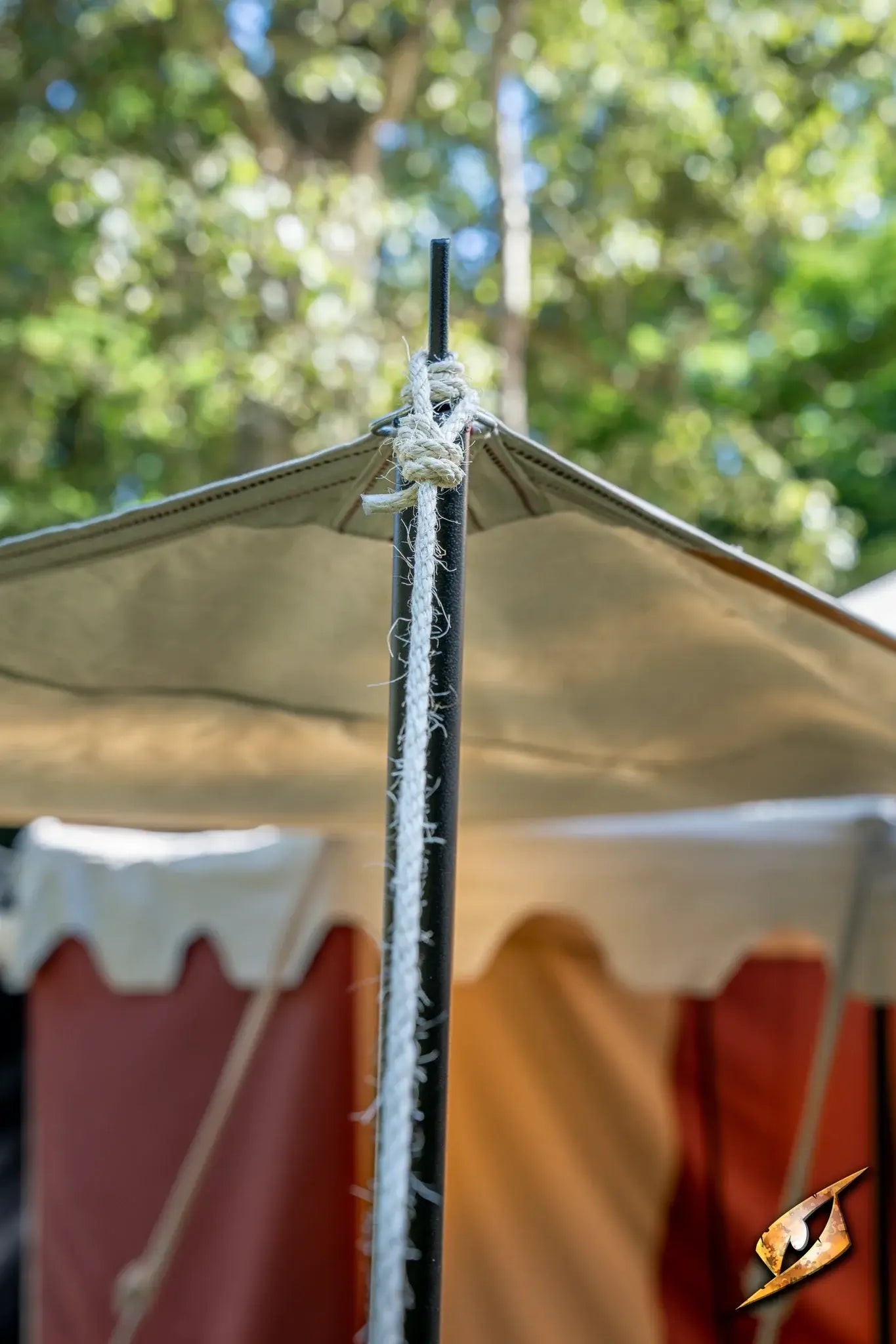 Tarpaulin supports and poles set up in a camping environment with green trees in the background.