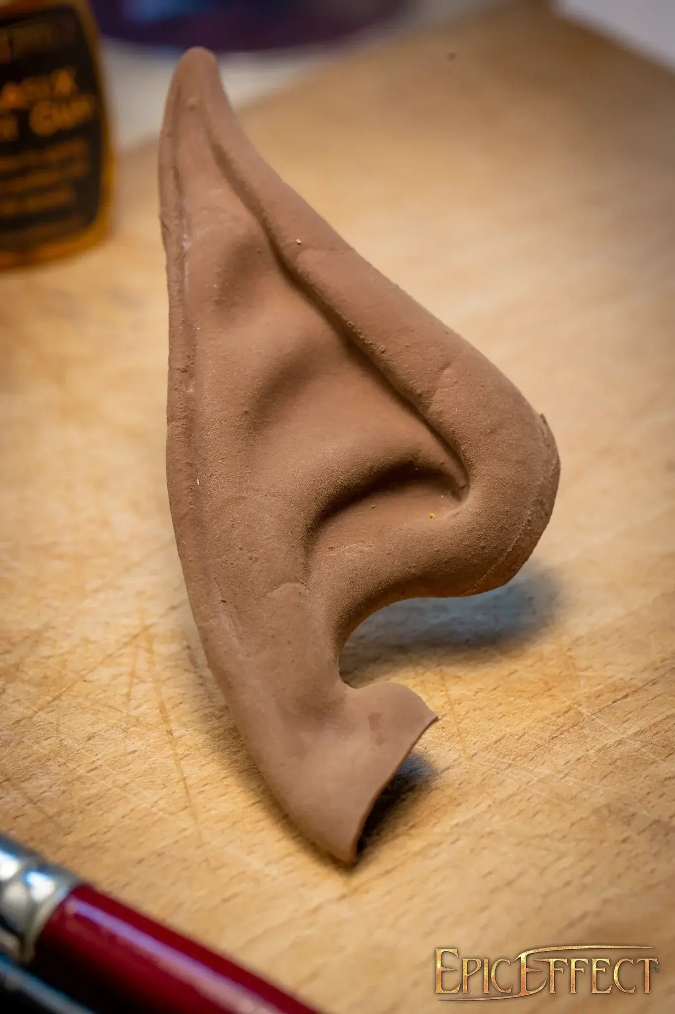 Elven Ears Long handmade ear sculpture displayed on wooden surface, showcasing intricate details and pointed design.