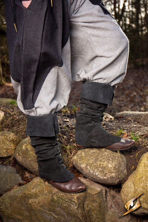 Theoderic gaiters worn by a person standing on rocks outdoors in a natural setting.