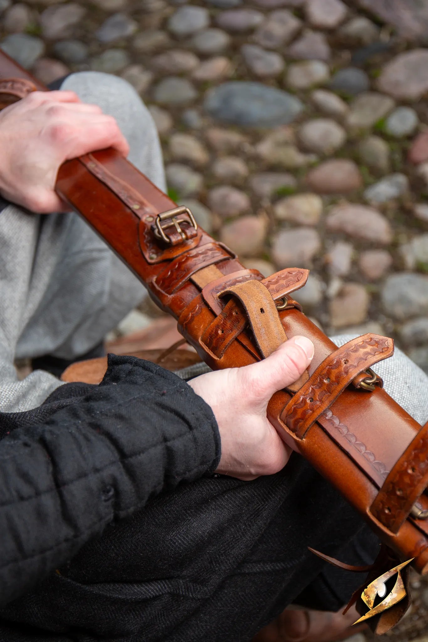 Close-up of hands holding a beautifully crafted Adjustable Scabbard, showcasing fine leatherwork and detailing.