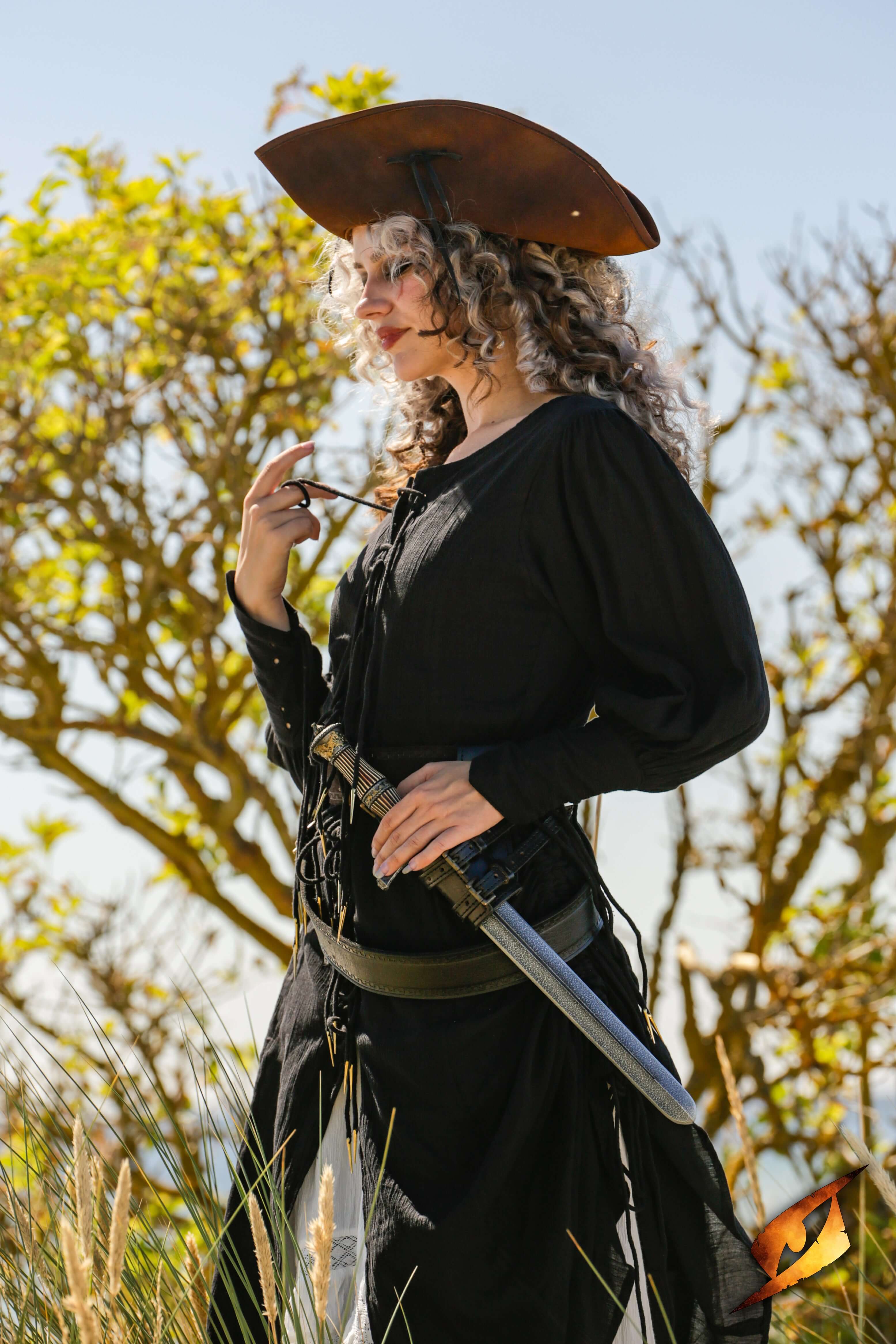A woman in a black outfit with a blocking dagger at her waist, showcasing a pirate-themed style outdoors.
