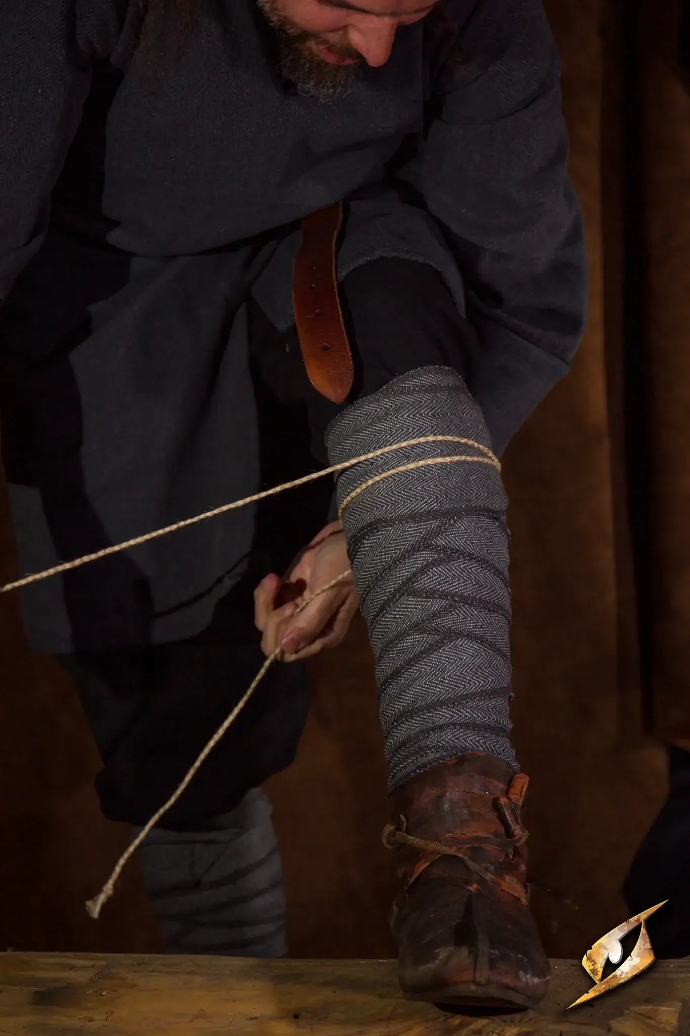A person adjusting Woodland Leg Wraps as they prepare for a journey, showcasing traditional attire and eco-friendly styles.