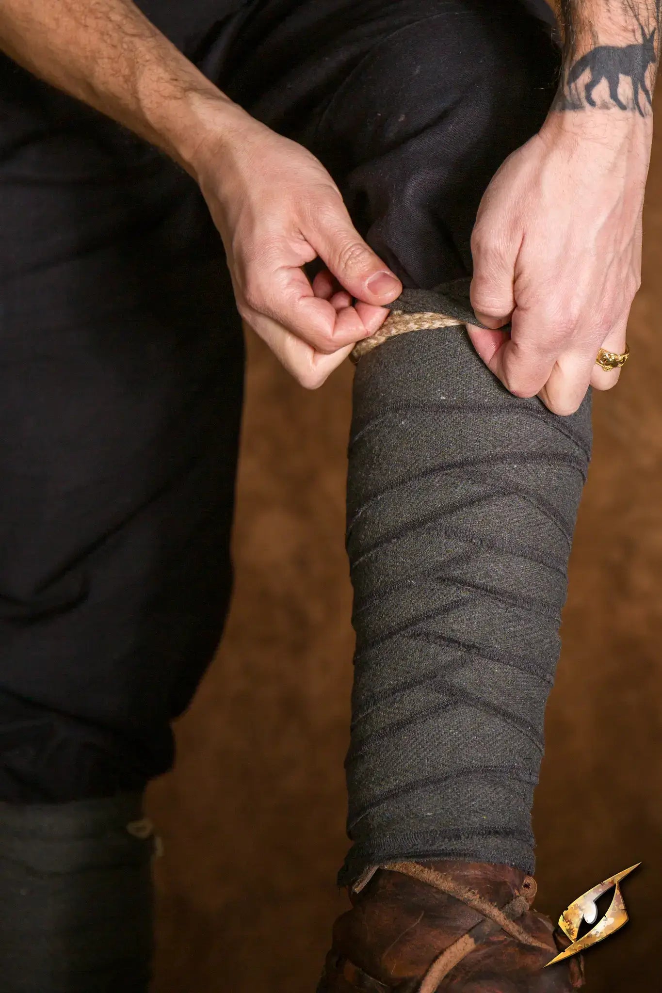 A person adjusting Woodland Leg Wraps on their leg, showcasing the intricate detailing and fit.