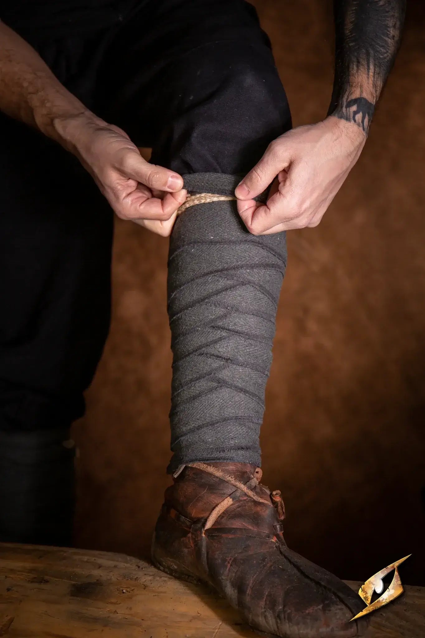 A person fastening Woodland Leg Wraps around their leg, showcasing the product in a dynamic, practical setting.