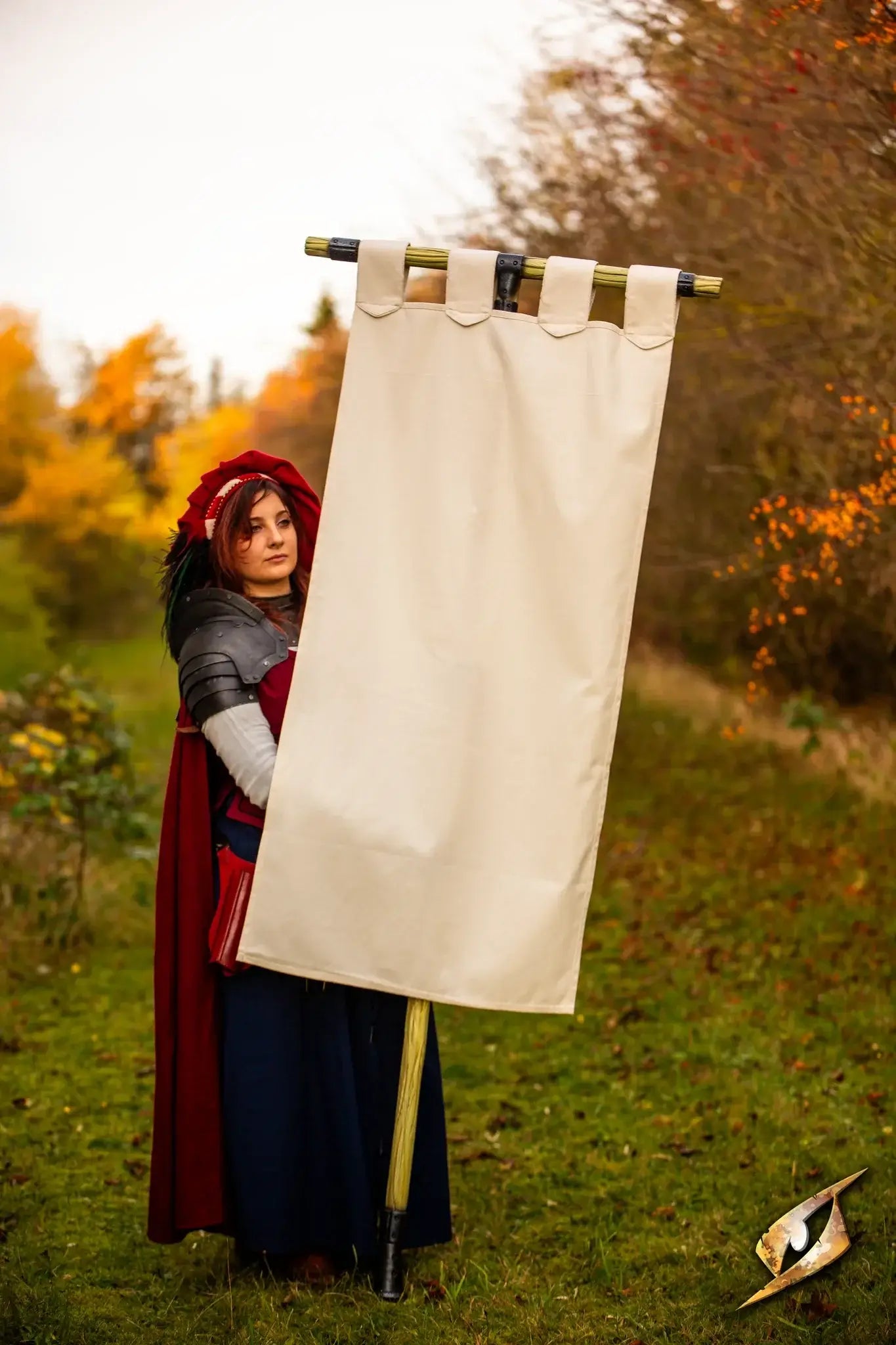 A person in costume holding a blank Battle Standard - T-Top in a scenic outdoor setting.