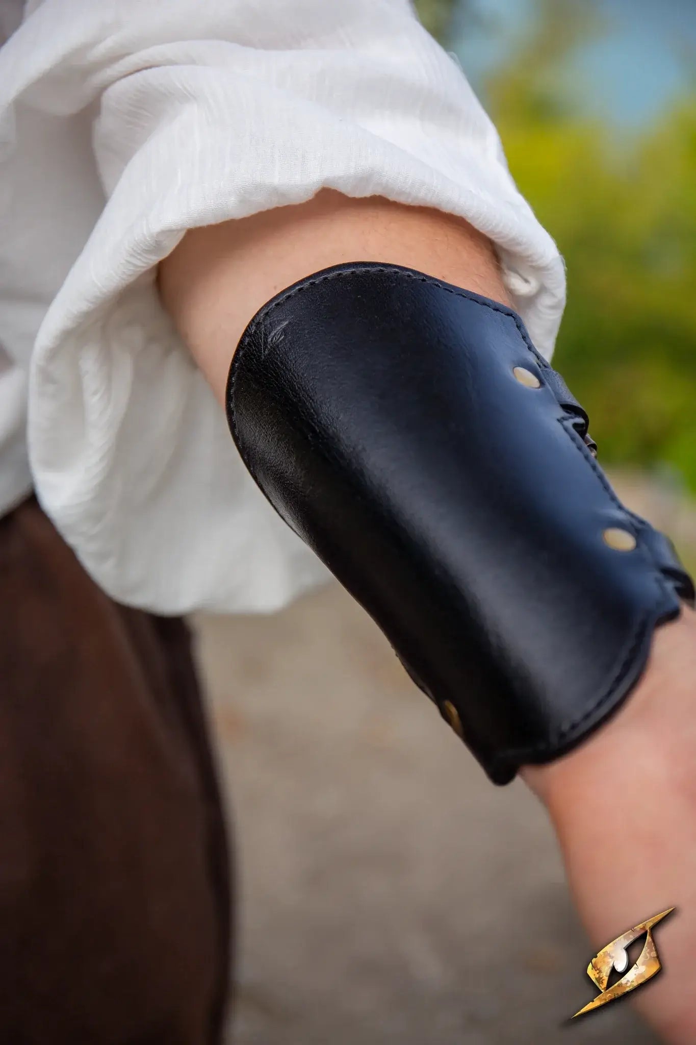 Close-up of an Archery Bracer worn on the arm, featuring black leather and bronze snaps for archery support.