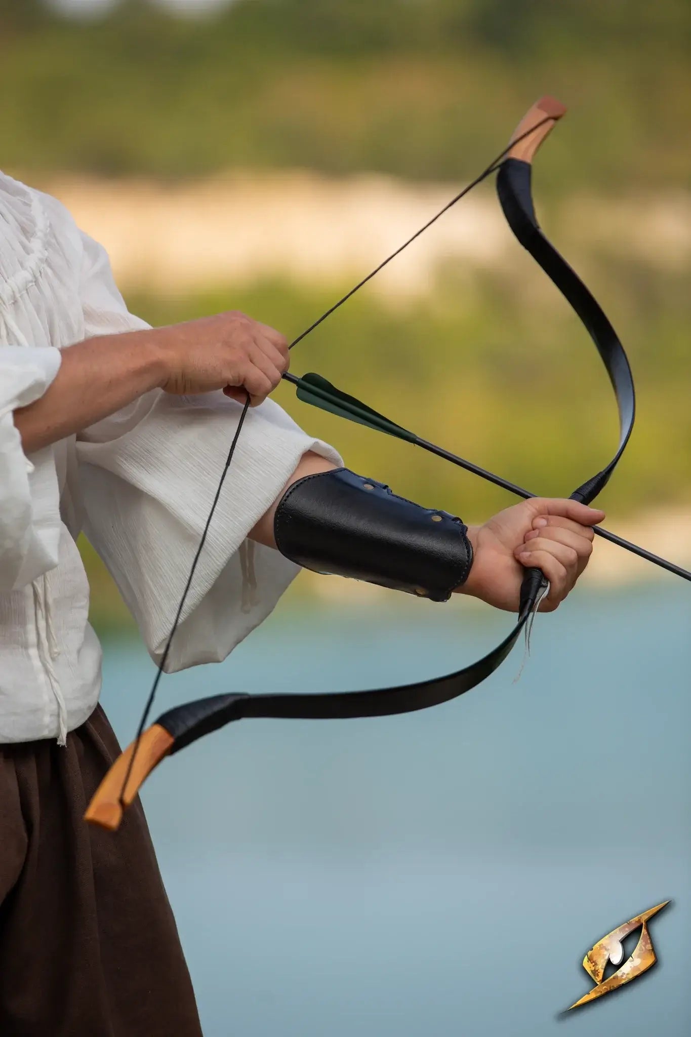 Person wearing an Archery Bracer while drawing a bow, set against a natural outdoor backdrop.