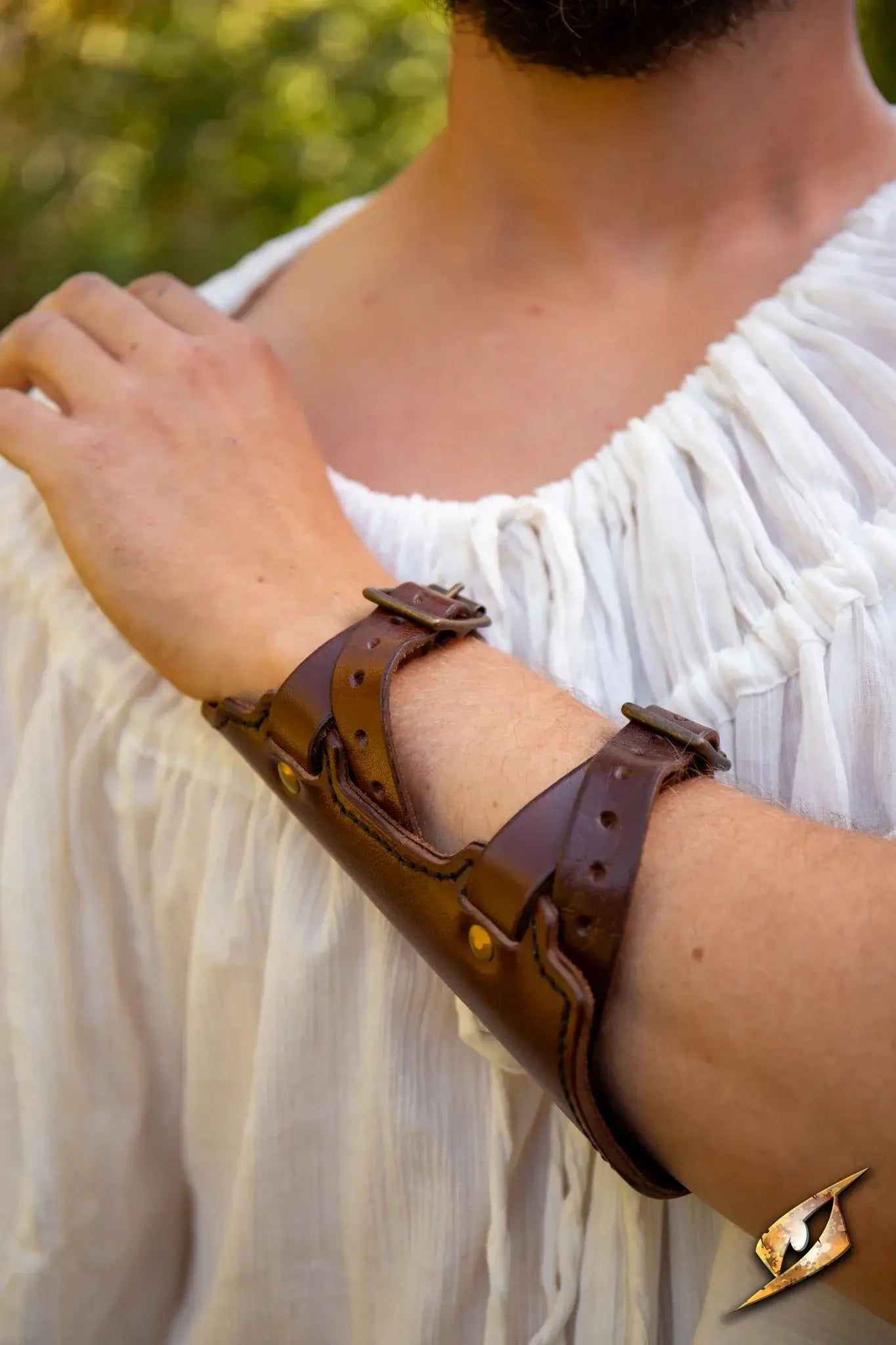 Close-up of a leather Archery Bracer worn on a person's arm outdoors.