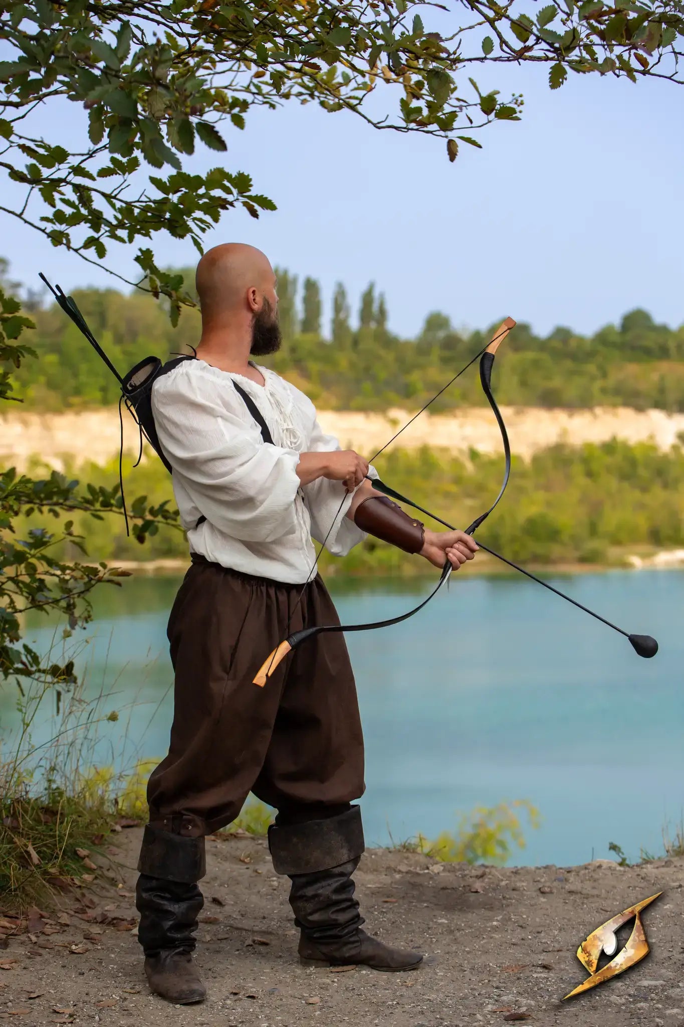 Man aiming with a bow in natural setting, showcasing an Archery Bracer on his arm.