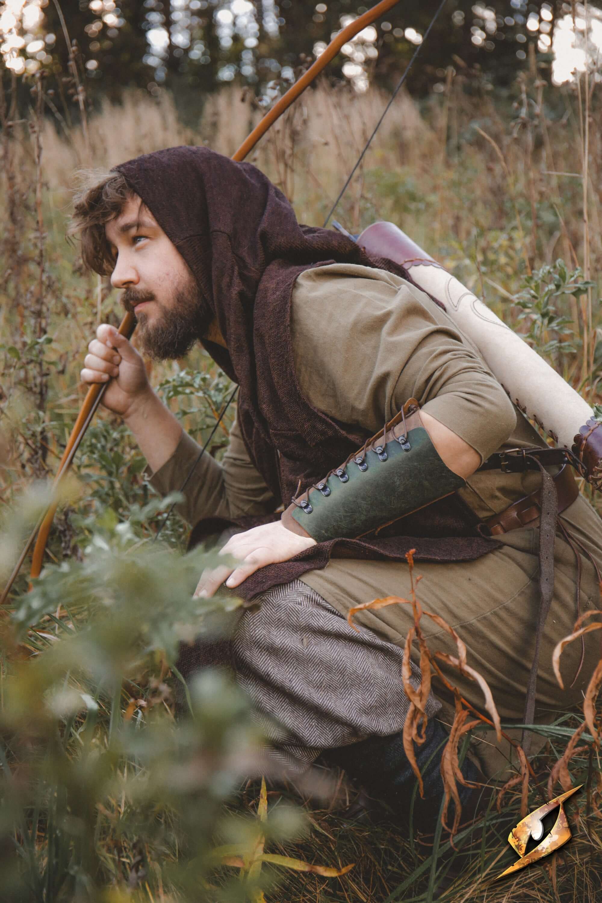 Man wearing Glade Warden Bracer in a forest setting, preparing to shoot an arrow.
