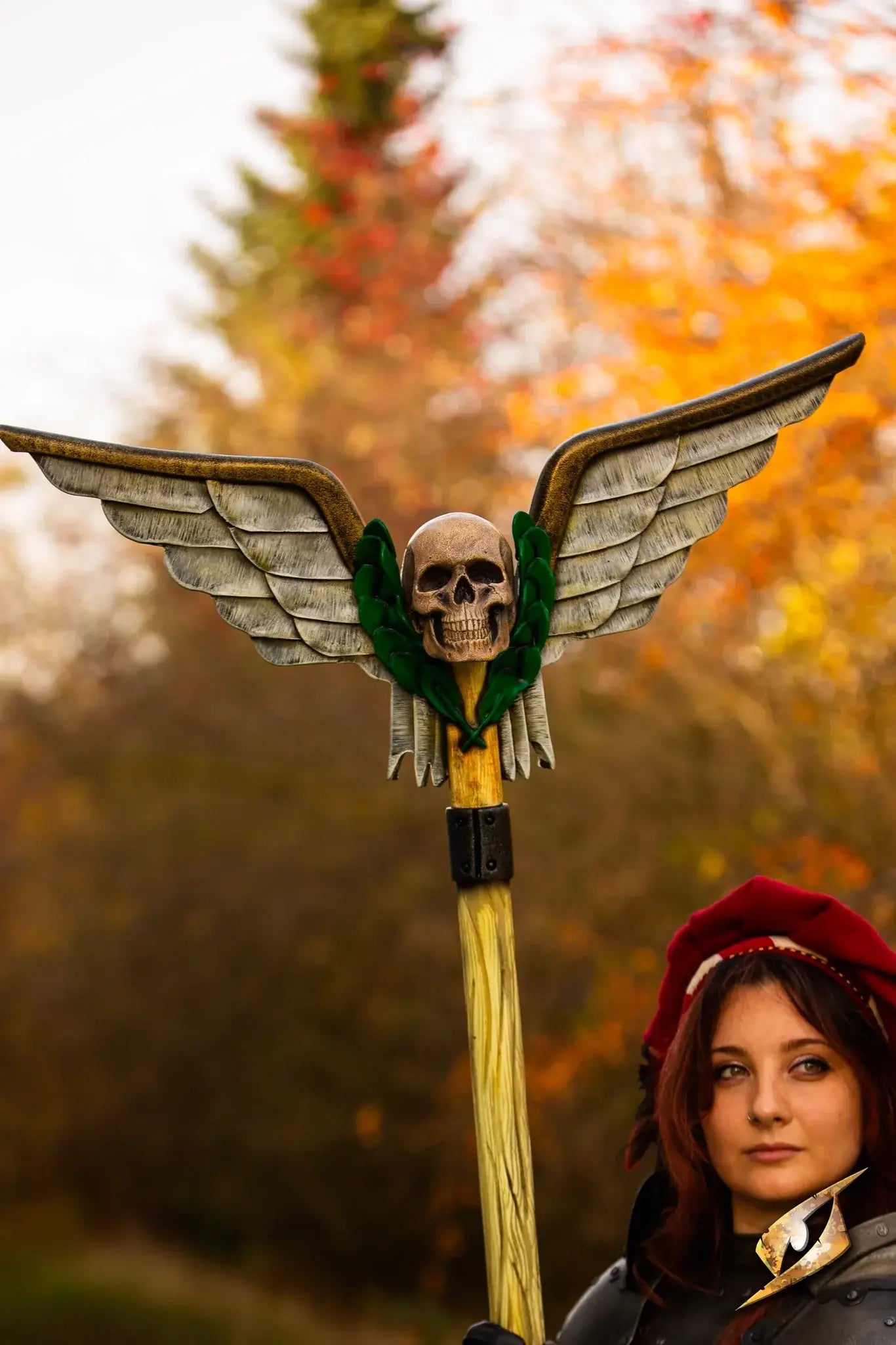 Battle Standard - Winged Skull Top held by a woman in a forest setting, featuring a winged skull design.