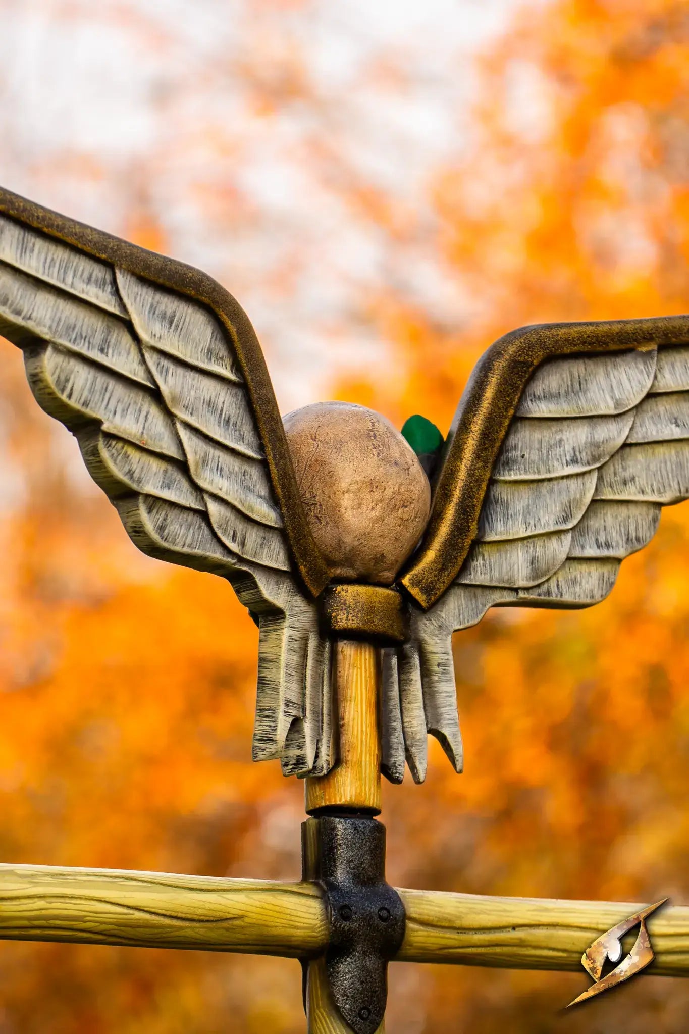 Battle Standard - Winged Skull Top featuring detailed wings and an ornamental sphere against a vibrant autumn background.