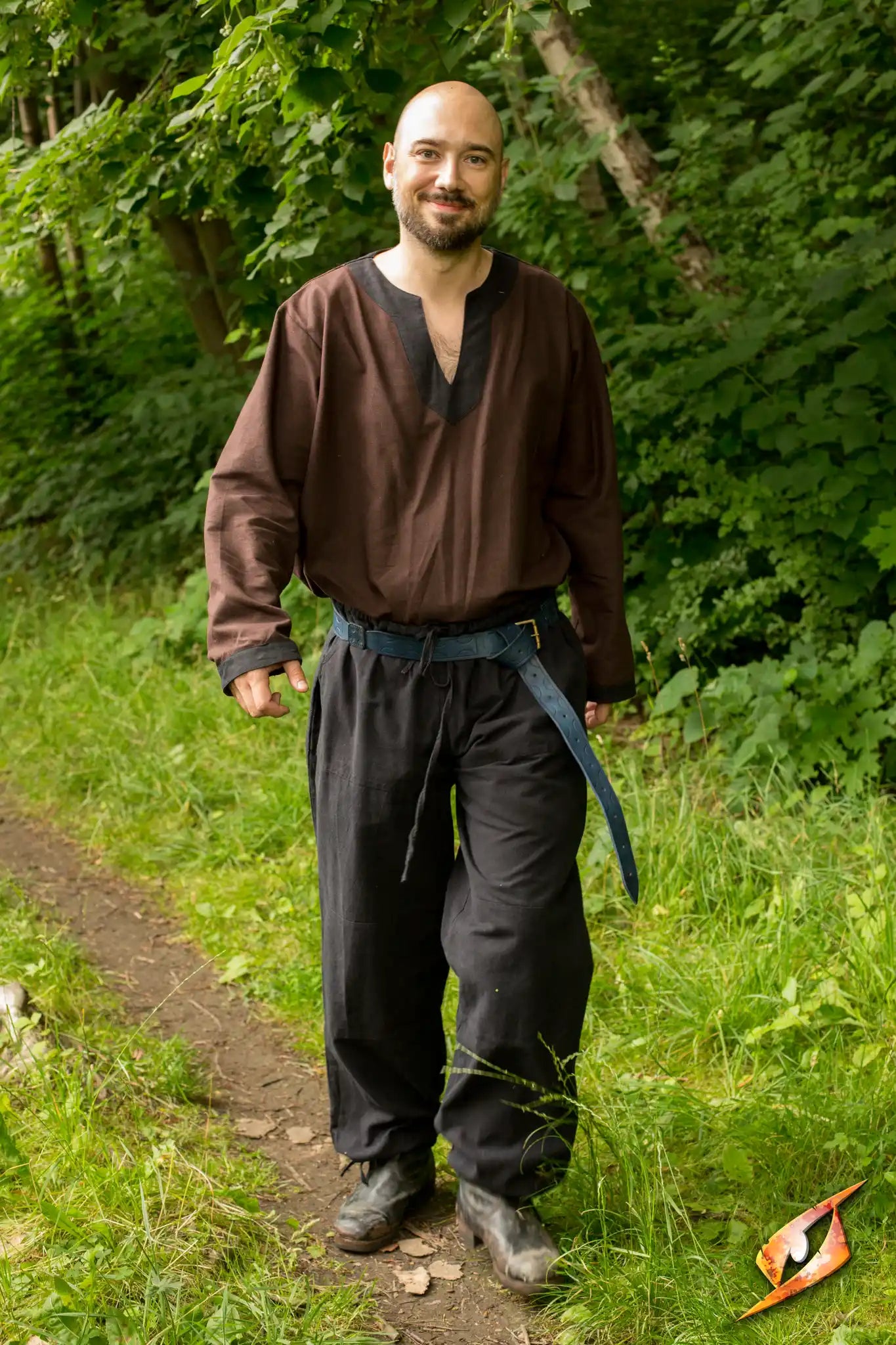 Man wearing Basic Pants and a dark shirt walking through a forest path.