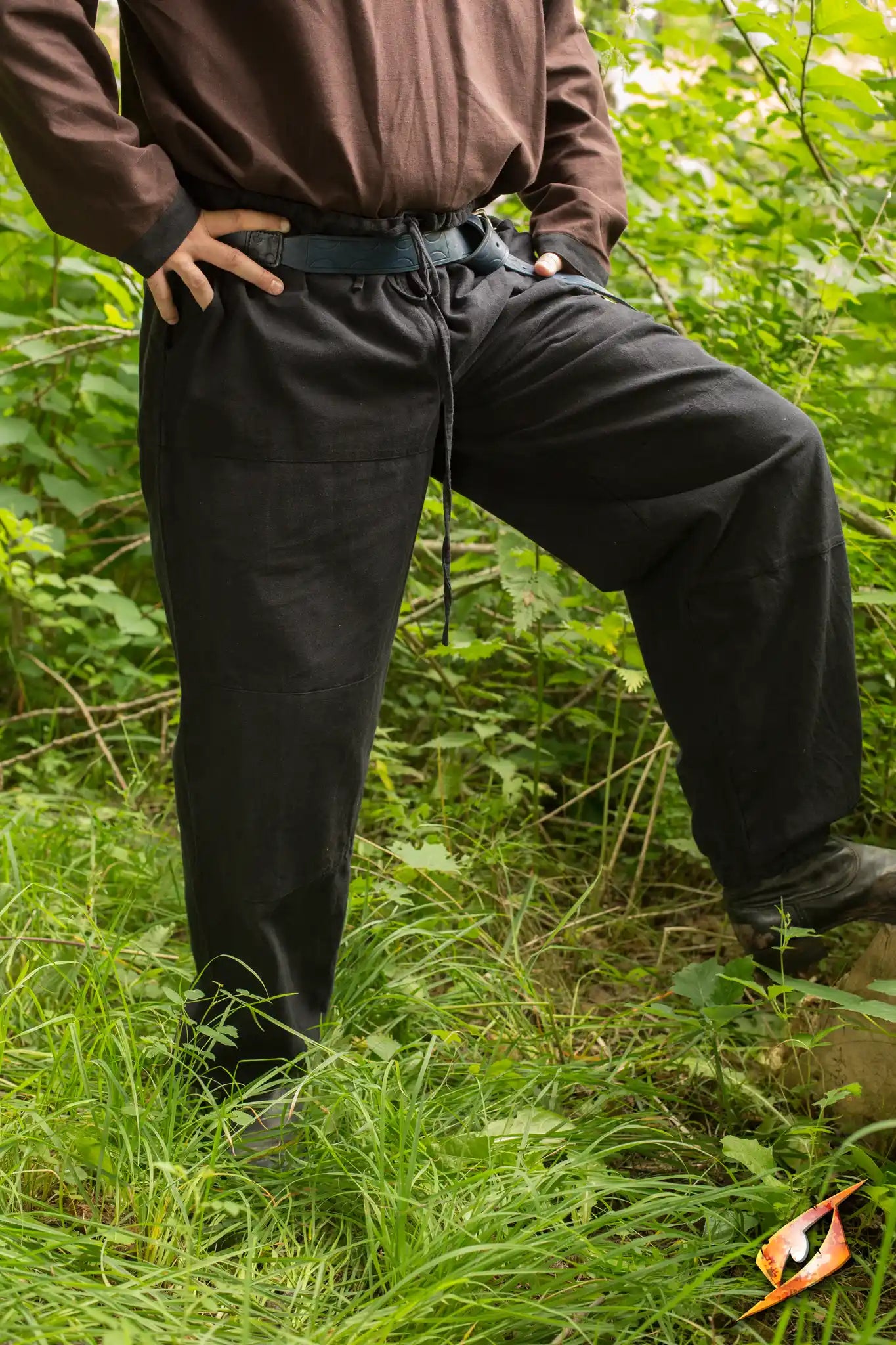 Man wearing Basic Pants in a green outdoor setting, standing confidently with hands on hips.