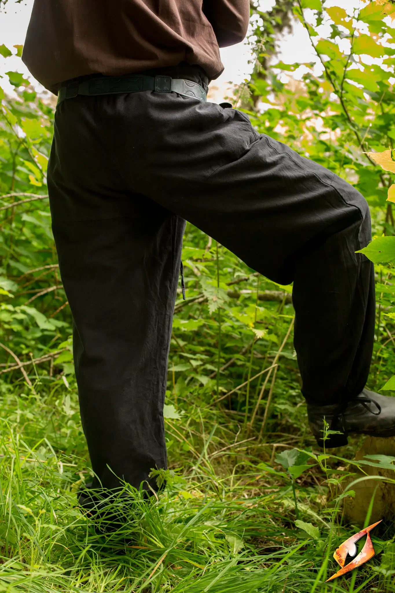 A person wearing Basic Pants stands amidst lush green foliage, showcasing outdoor style and durability.