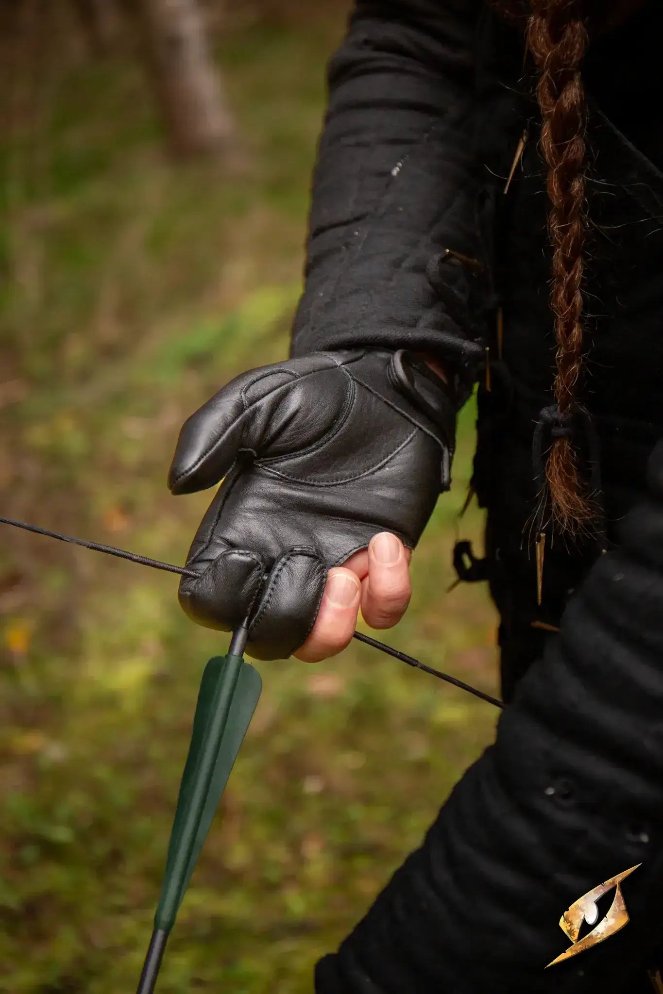 Archery Half-glove worn by an archer gripping an arrow while preparing to shoot outdoors.