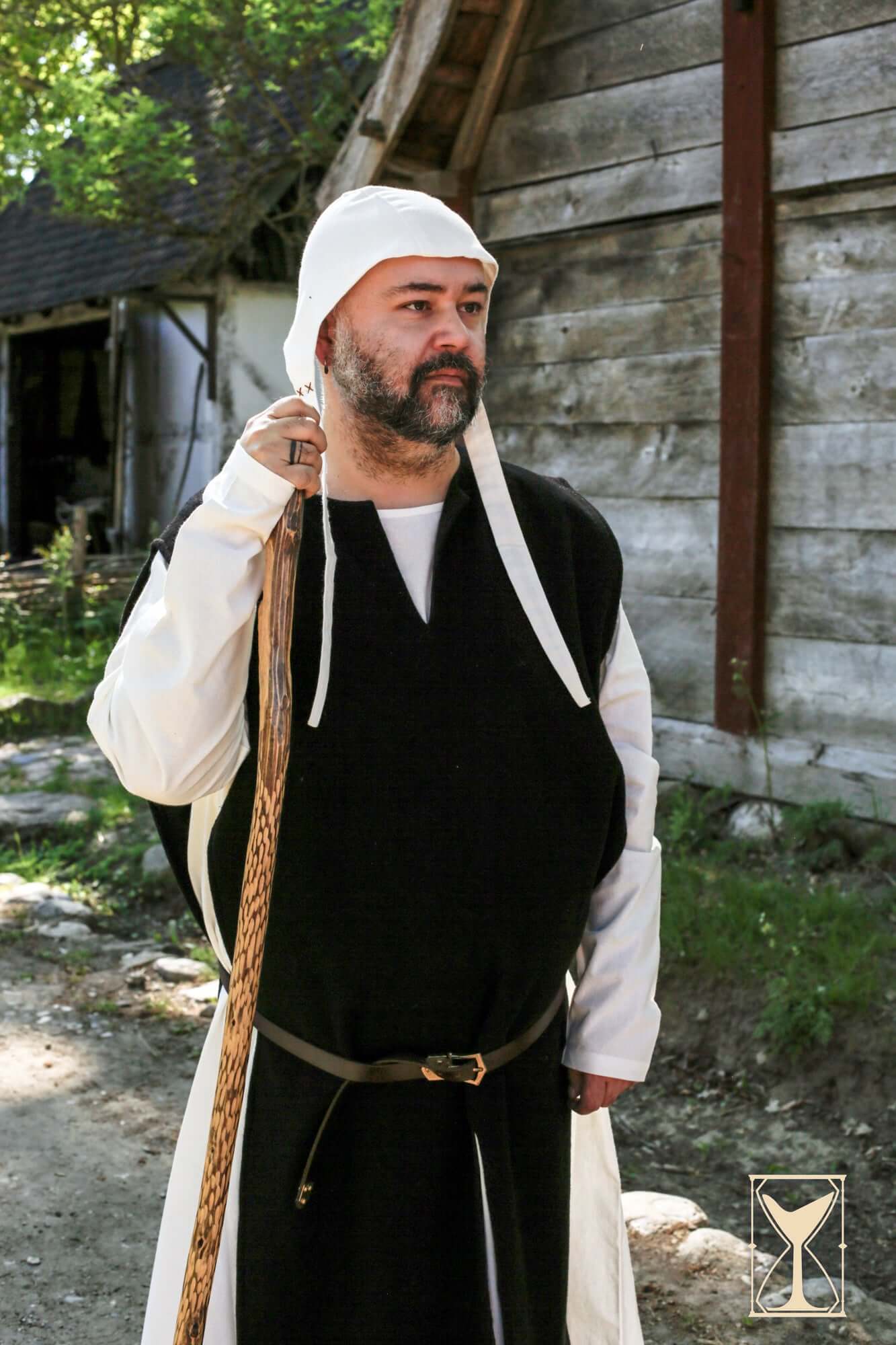 Man wearing Cyclas Bernard over-tunic, embodying medieval style and history in a natural setting.