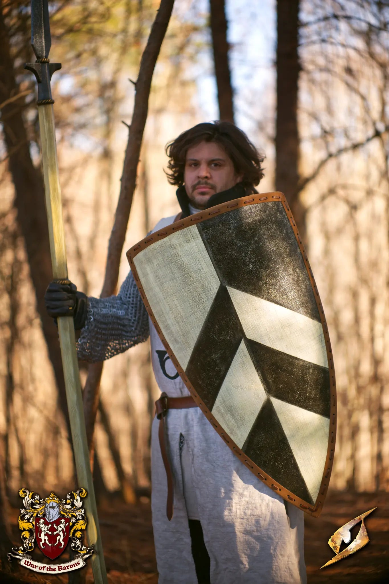A LARP participant holding the Baron's Shield in a forest, showcasing medieval design and historical aesthetics.