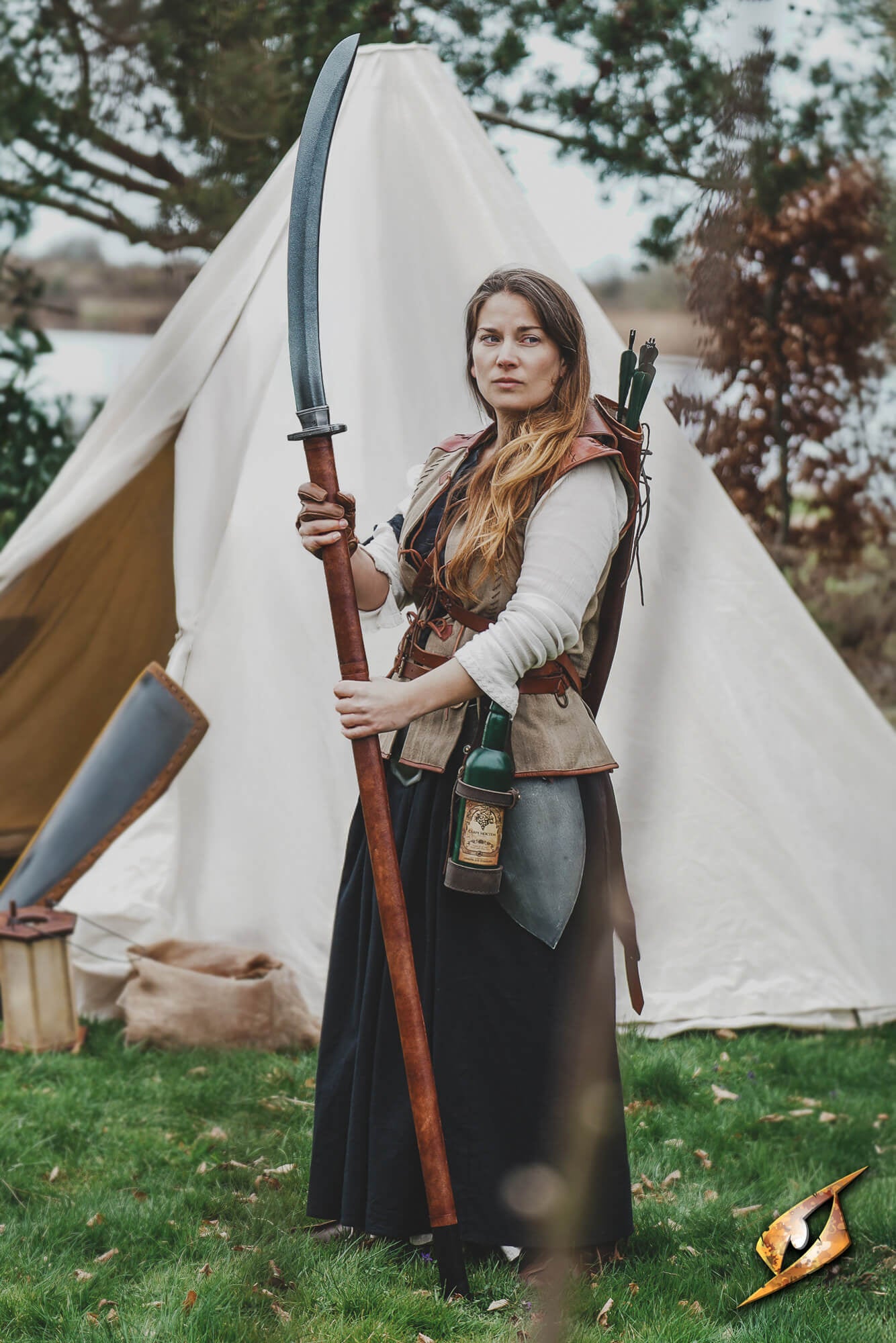 Naginata compact held by a woman in historical attire near a tent in a natural setting.
