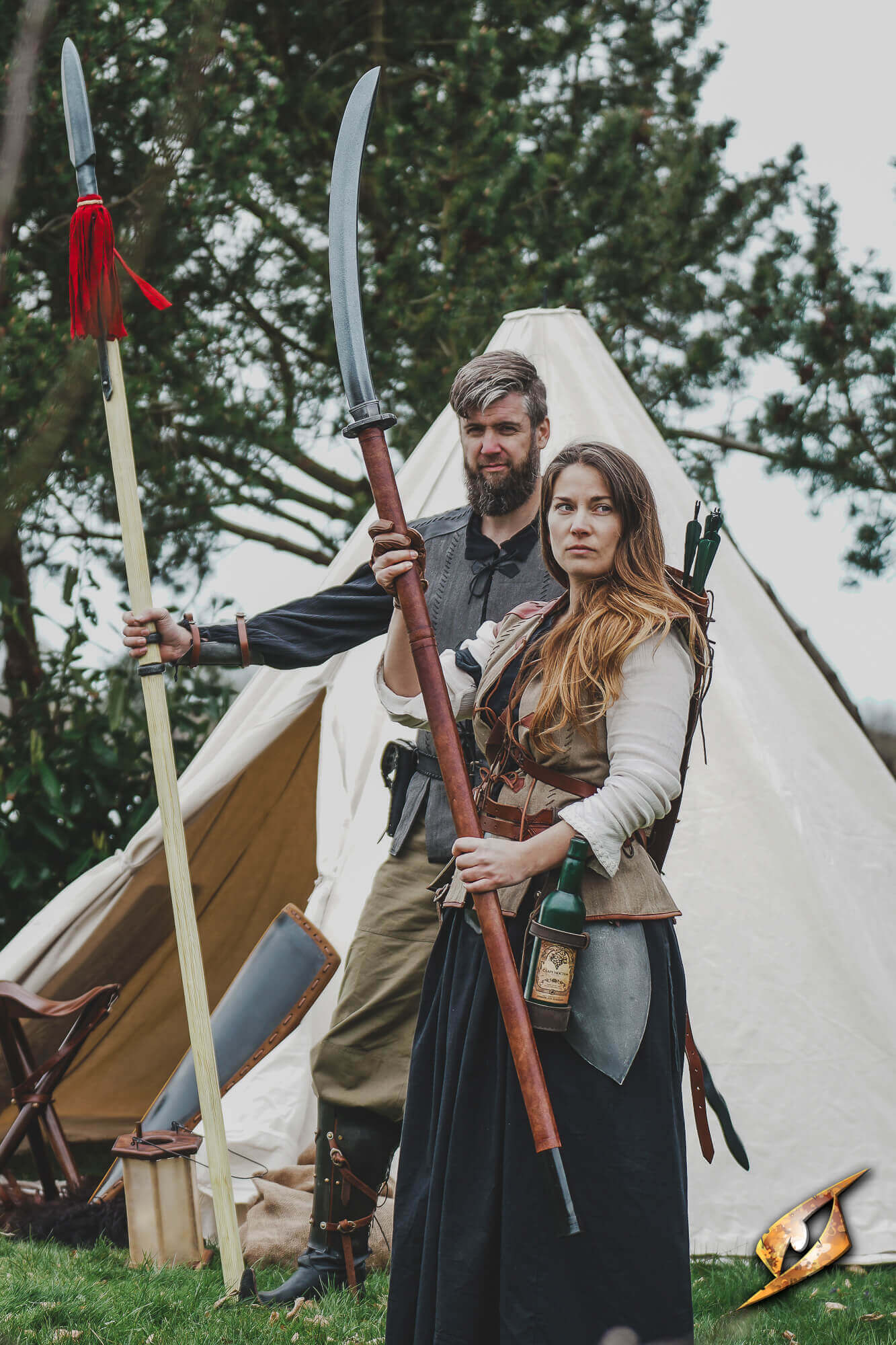 Naginata compact held by a woman, alongside a man with a spear, in a camp setting.