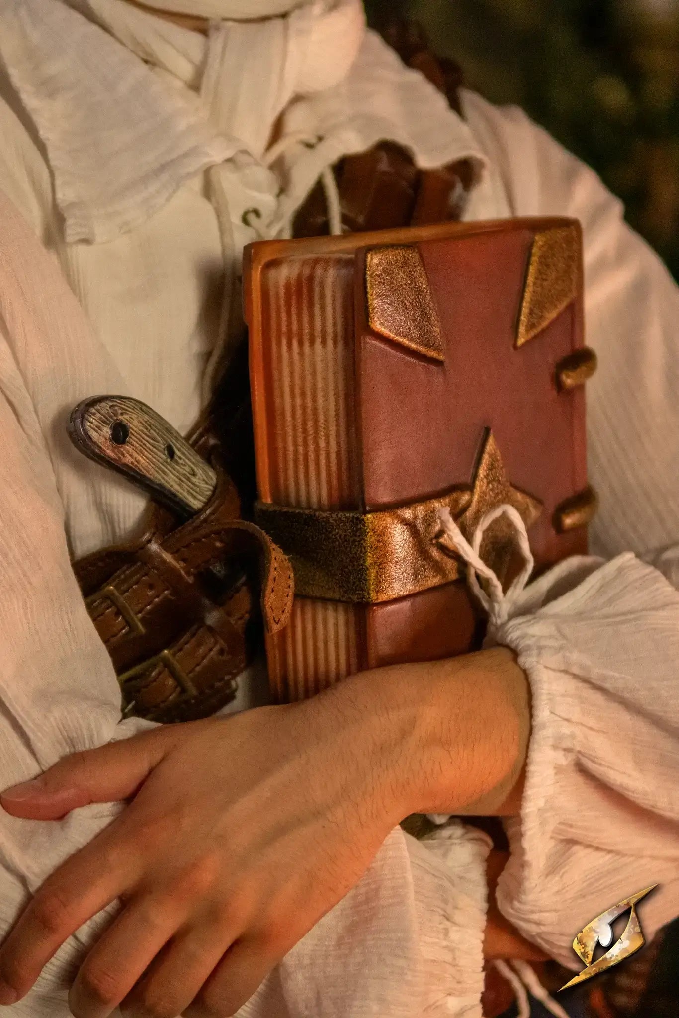 Book held in hands, resembling worn leather with metal accents for LARP adventures.