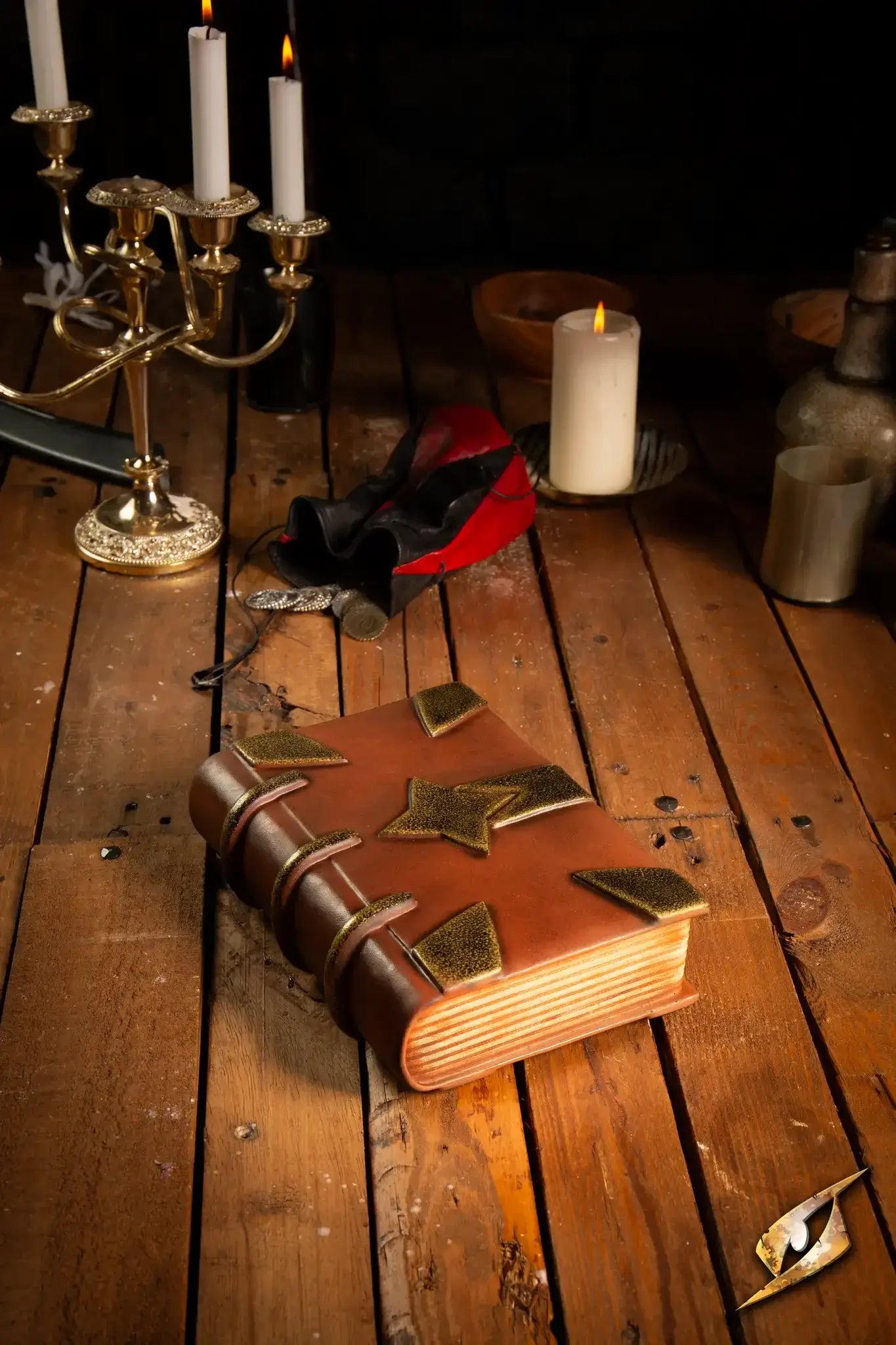 Book on a wooden table with candles, featuring a leather cover and metal corner protectors.