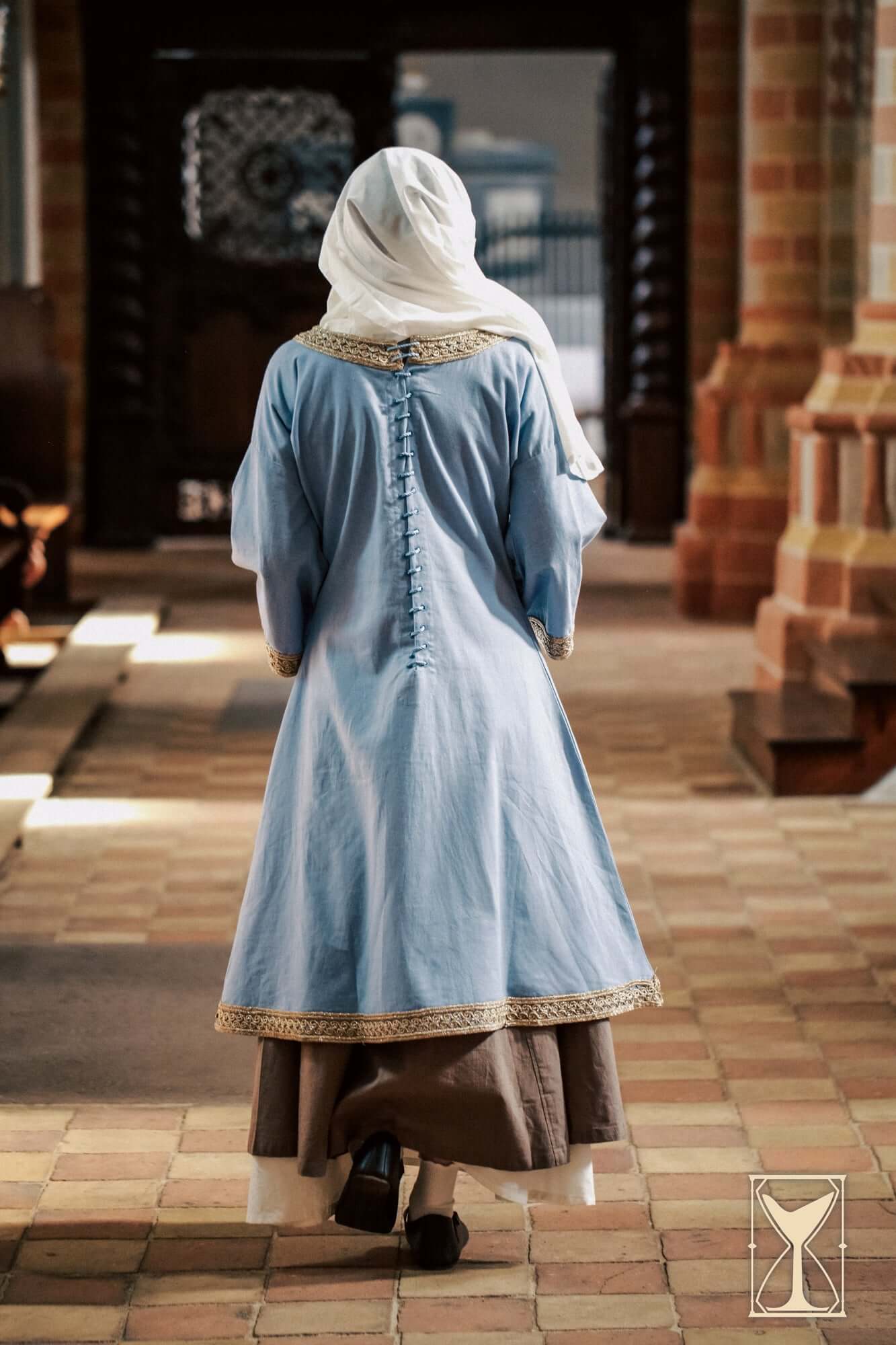 Overtunic Matilde worn from behind, showcasing wide sleeves and woven patterned trim.