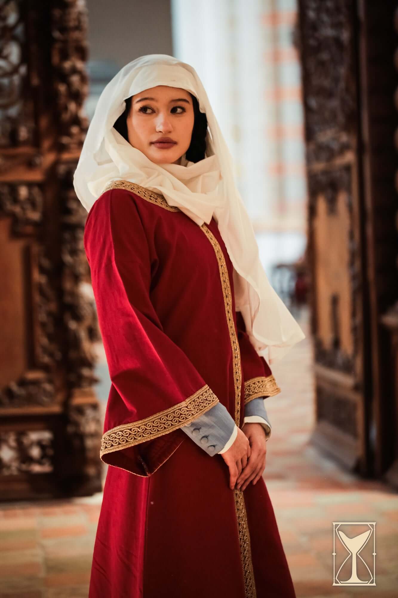 Overtunic Matilde modeled by a woman, featuring wide sleeves and woven patterned trim in a historical setting.