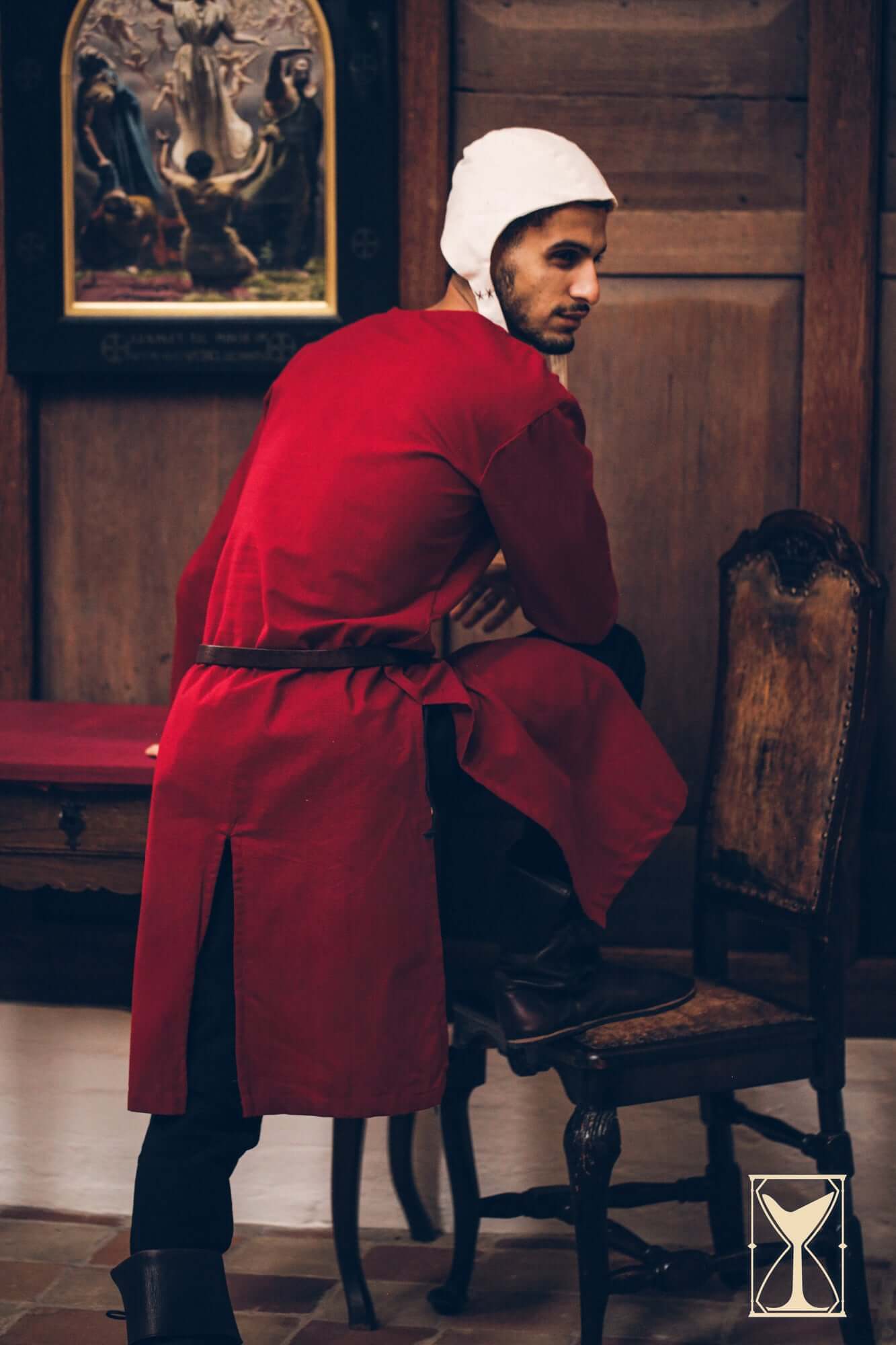 Man wearing a Medieval Riding Tunic in red color, demonstrating the tunic's deep splits for ease of movement.