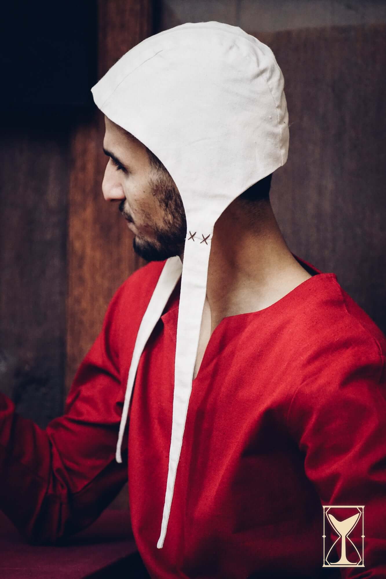 Medieval Riding Tunic model wearing a white hooded cap alongside a red tunic.