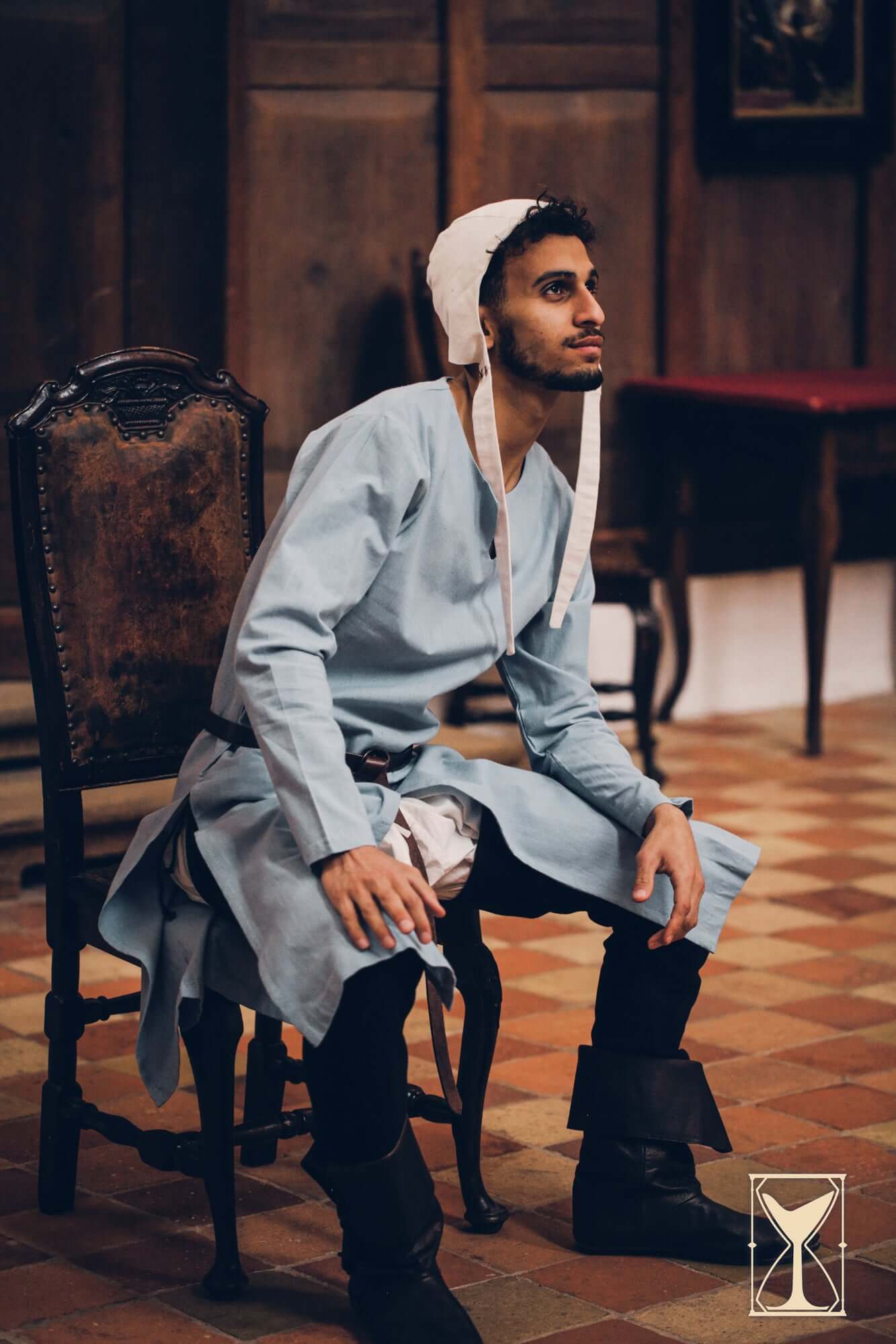 Man seated in a Medieval Riding Tunic, showcasing historical fashion for Medieval period reenactments.