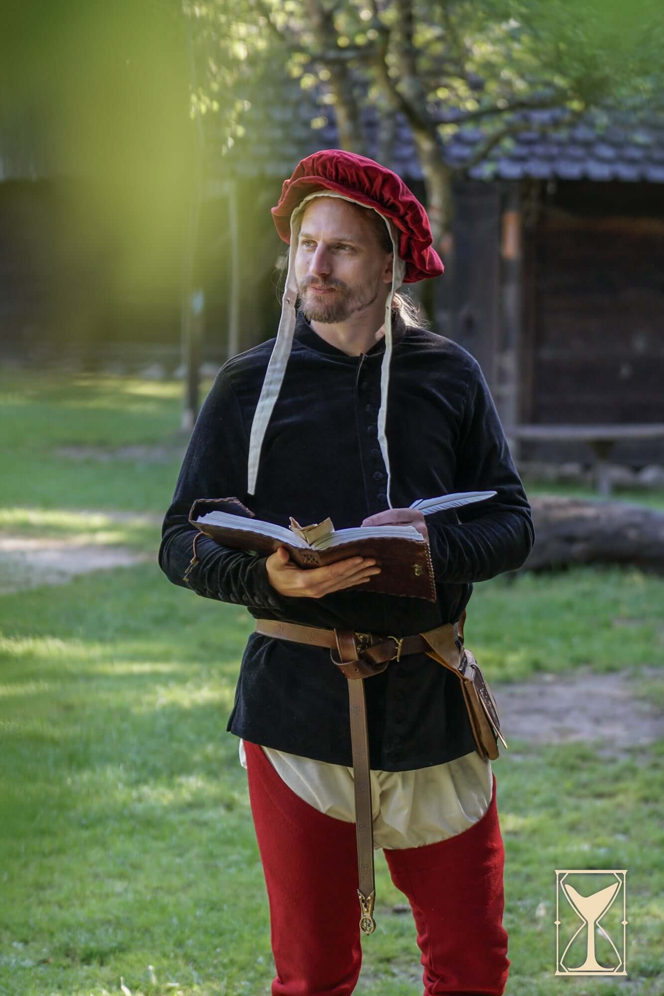 Cotehardie Bonifacio worn by a man reading a book in a picturesque outdoor setting.