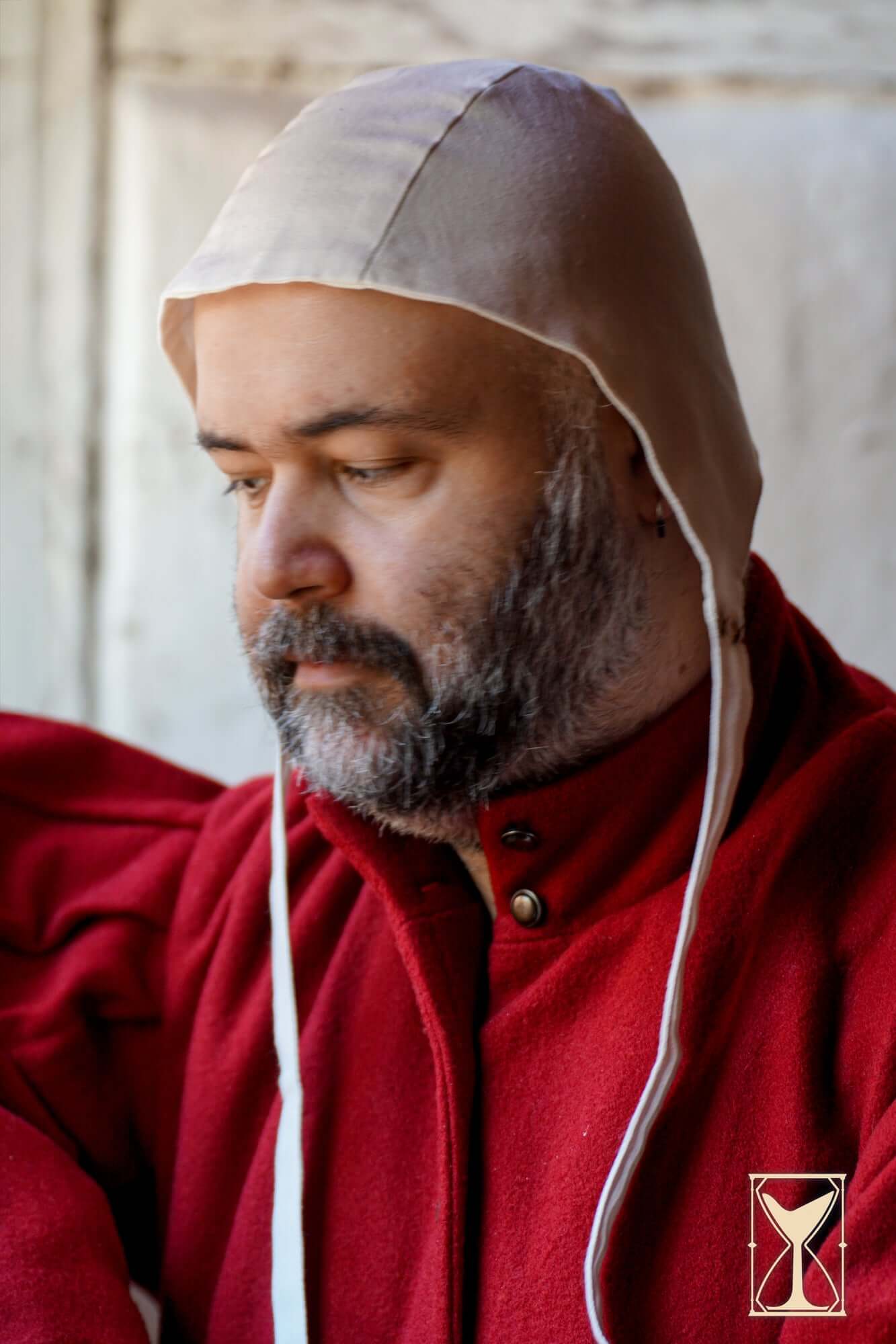 Coif 12th century worn by a man in a red coat, showcasing traditional medieval headwear.